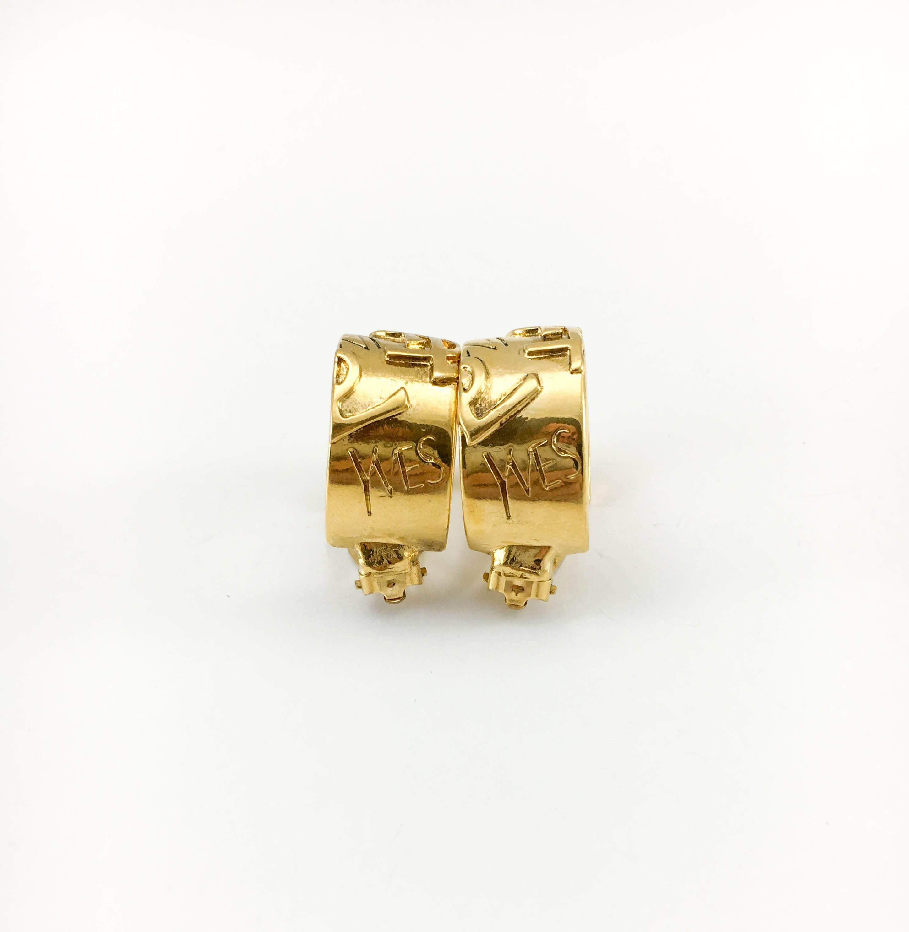 Vintage Yves Saint Laurent Gold-Plated Logo Clip-On Hoop Earrings. These stylish earrings by Yves Saint Laurent date back from the 1980’s. Made in gold-plated metal, these wide hoops feature the iconic YSL logo and the word ‘Yves’. YSL signed on the