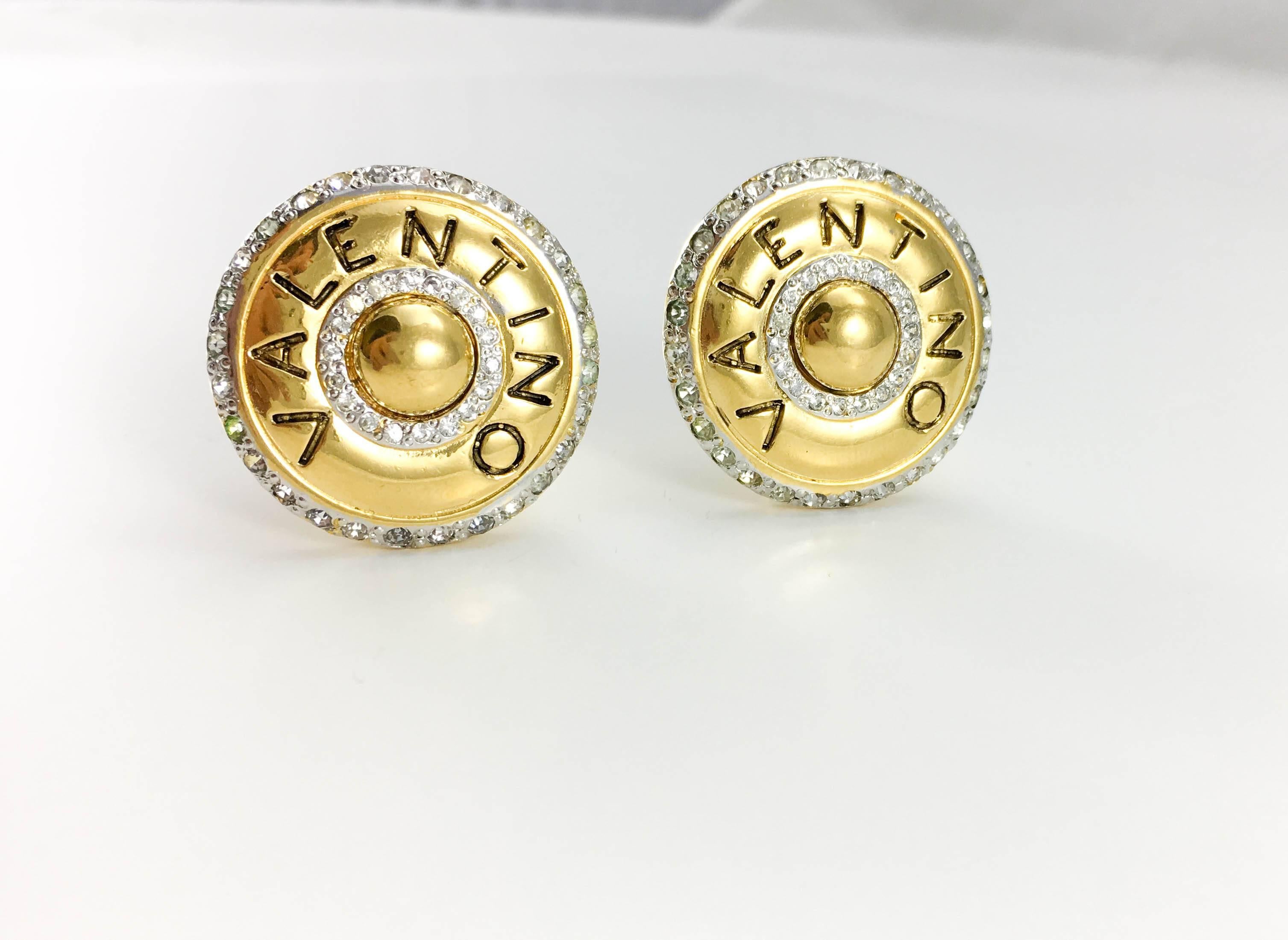 Vintage Valentino Gilt Metal and Rhinestone Round Clip-On Earrings. These very stylish Valentino earrings date back from the 1980’s. Round, they are made in gilt metal, are embellished with rhinestones along the edge, as well as forming an inner