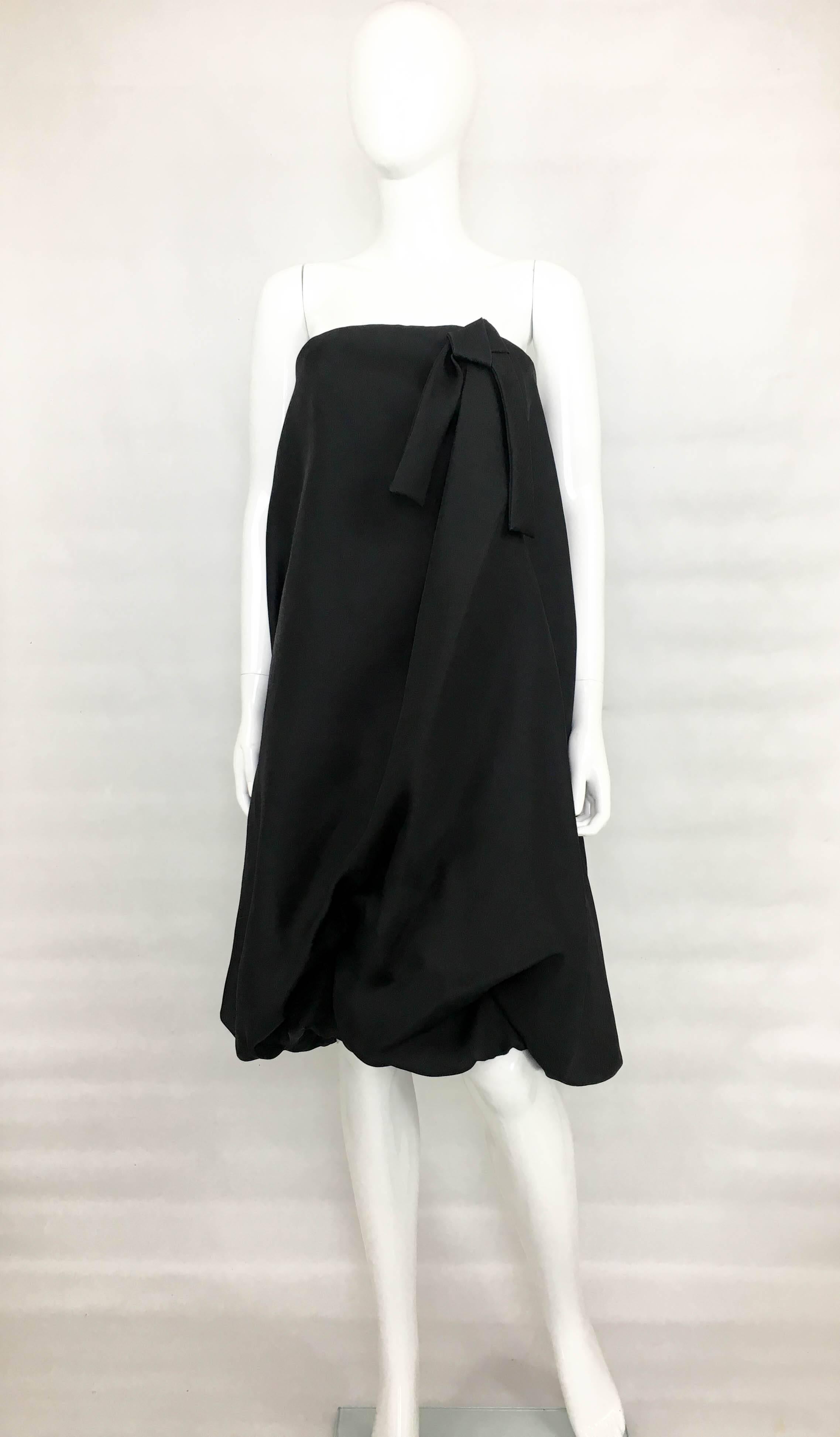 Important Vintage Balenciaga Black Gazar Cocktail Dress. This striking strapless dress by Balenciaga dates back from the late 1980’s. Made in black silk gazar, this hem-gathered balloon dress has an architectural and avantgarde silhouette. With