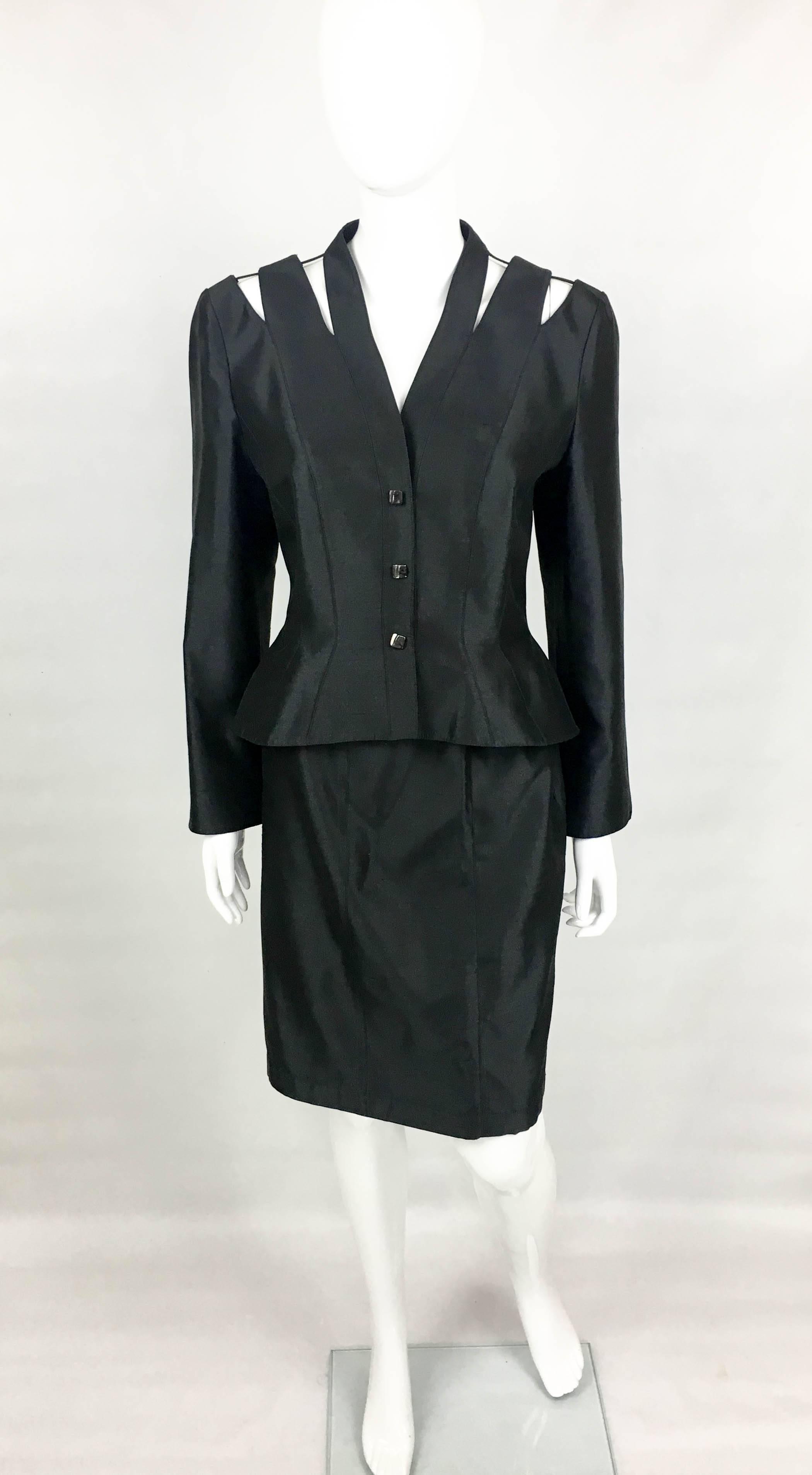 Vintage Mugler Black Silk Skirt Suit. This gorgeous suit by Thierry Mugler dates back from the 1990’s. Made in a black silk blend fabric, it consists of a knee length skirt and a long sleeve jacket. The jacket has a defined waist and it flares out,