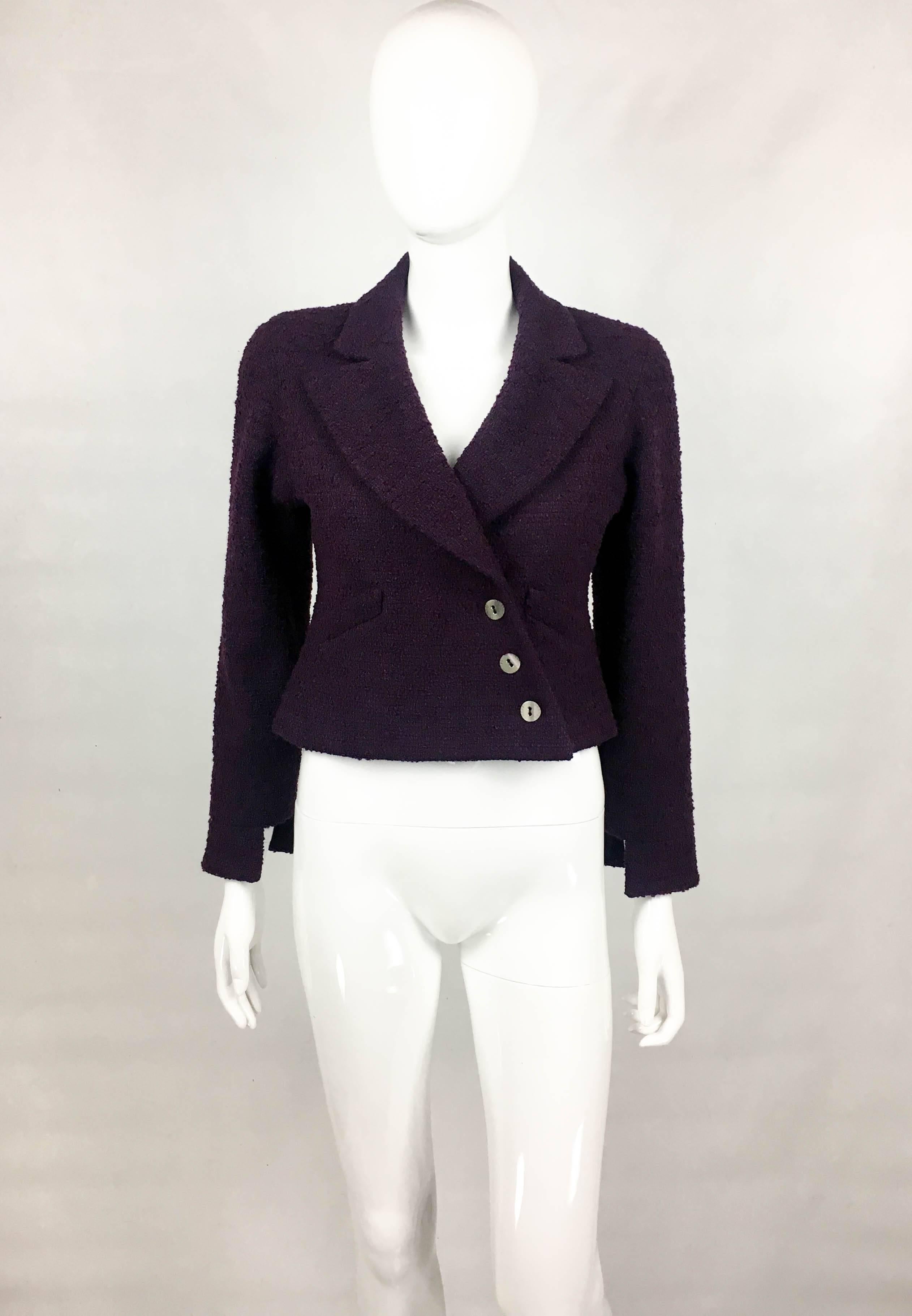 Chanel Deep Purple Bouclé Cropped Jacket. This striking jacket by Chanel is from the 2001 Fall / Winter collection. In deep purple bouclé, it has hoof cuffs, defined waist and asymmetric fastening. The buttons are silver-tone, curved and say