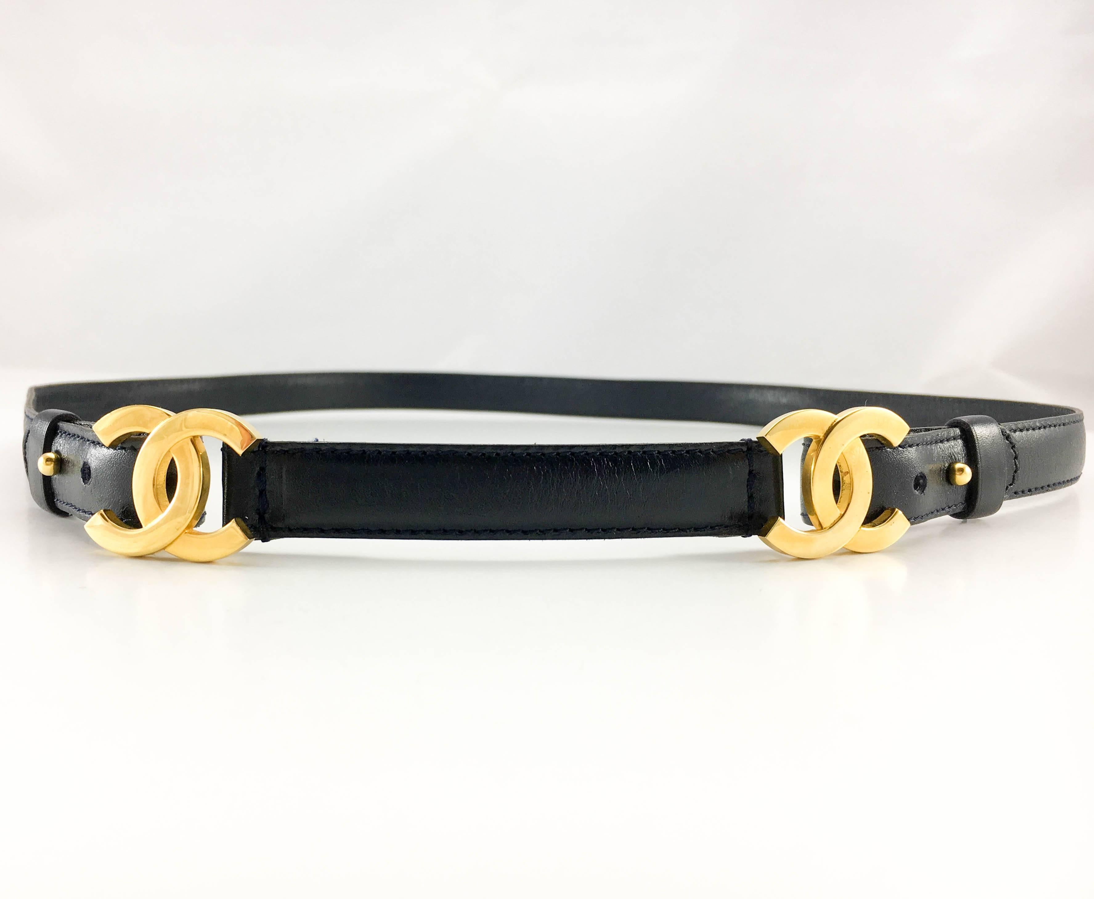 Chanel Navy Leather and Gilt Logo Belt. This delicate and stylish thin belt by Chanel is an understated way to add a dash of fashion glamour to a look. In navy blue leather, it features 2 gilt ‘CC’ logo buckles. 

Label / Designer: Chanel

Period:
