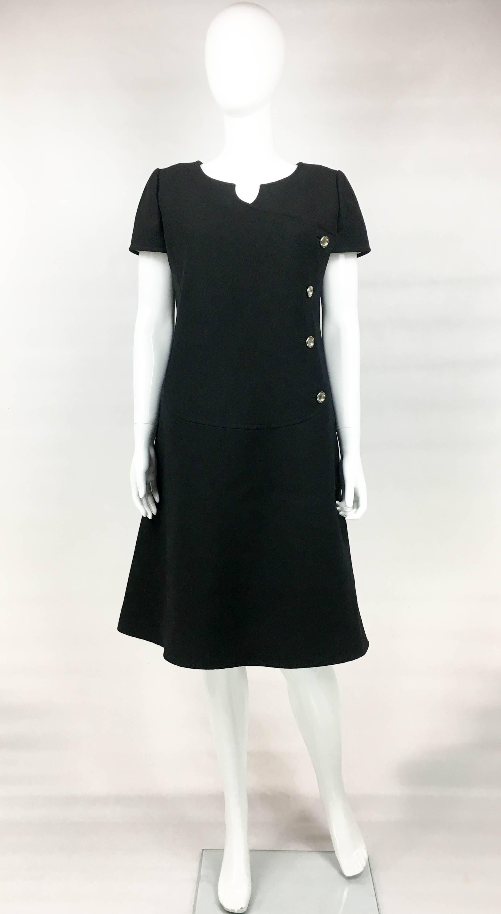 Vintage Courreges Black Wool Dress. This dress by Courreges dates back from the late 1960’s. Made in black wool, it has the iconic 60’s mod shape. It has round metal buttons fastening down one side of the bodice. Hidden zipper on the back. Labelled