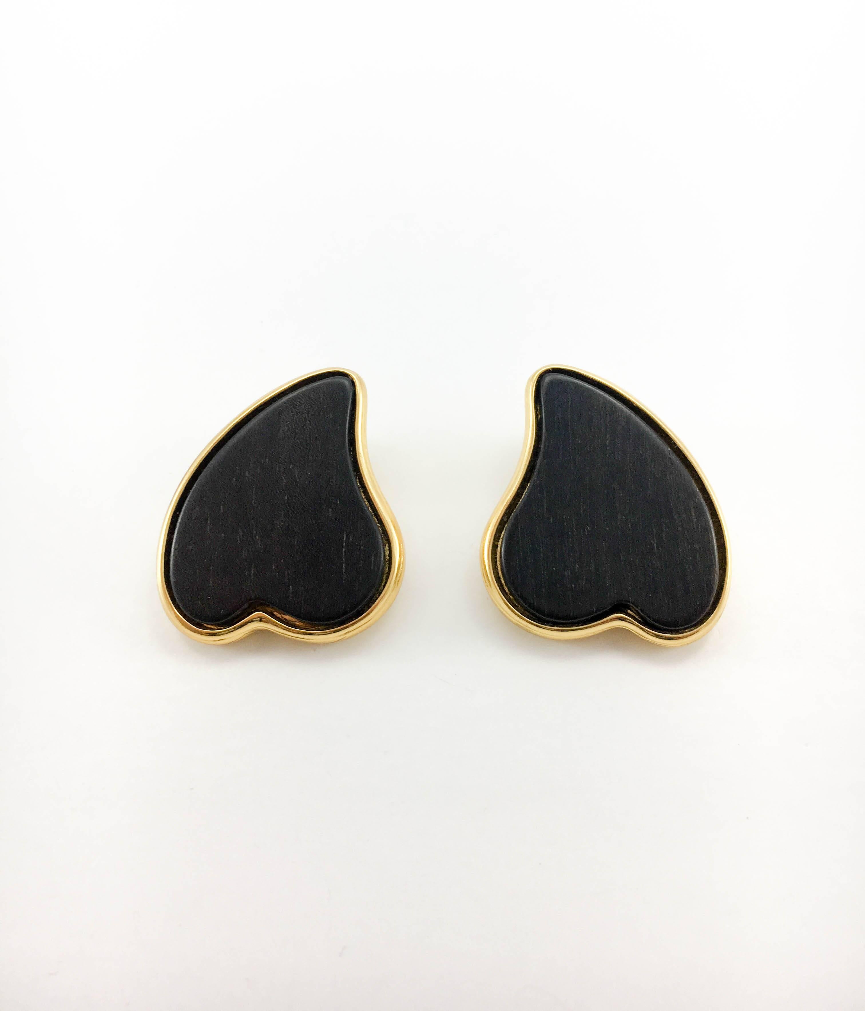 Vintage Yves Saint Laurent Gold-Plated Wood Heart Clip-On Earrings. These stylish earrings by Yves Saint Laurent date back from the 1980’s. Made in gold-plated metal, it features an inset black-wood heart. Signed and numbered (E8) on the back.