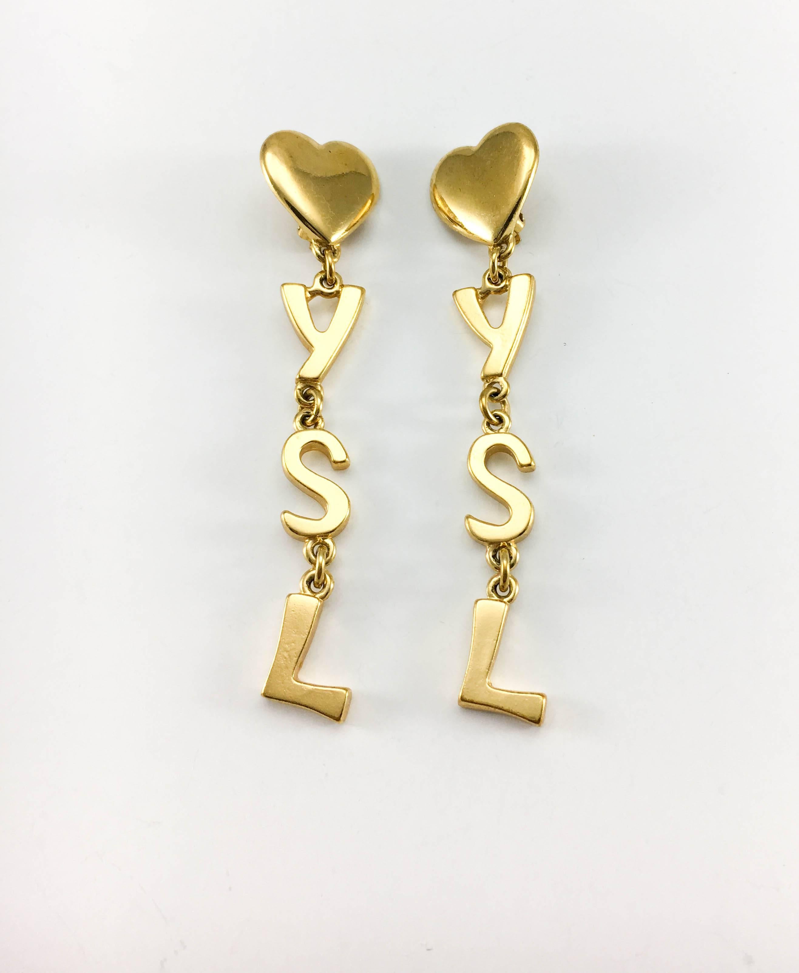 Vintage Yves Saint Laurent Dangling Clip-On Earrings. These fabulous long dangling earrings by Yves Saint Laurent date back from the 1980’s. As iconic as they can be, the design of these gold-plated earrings features the YSL letters. YSL signed and