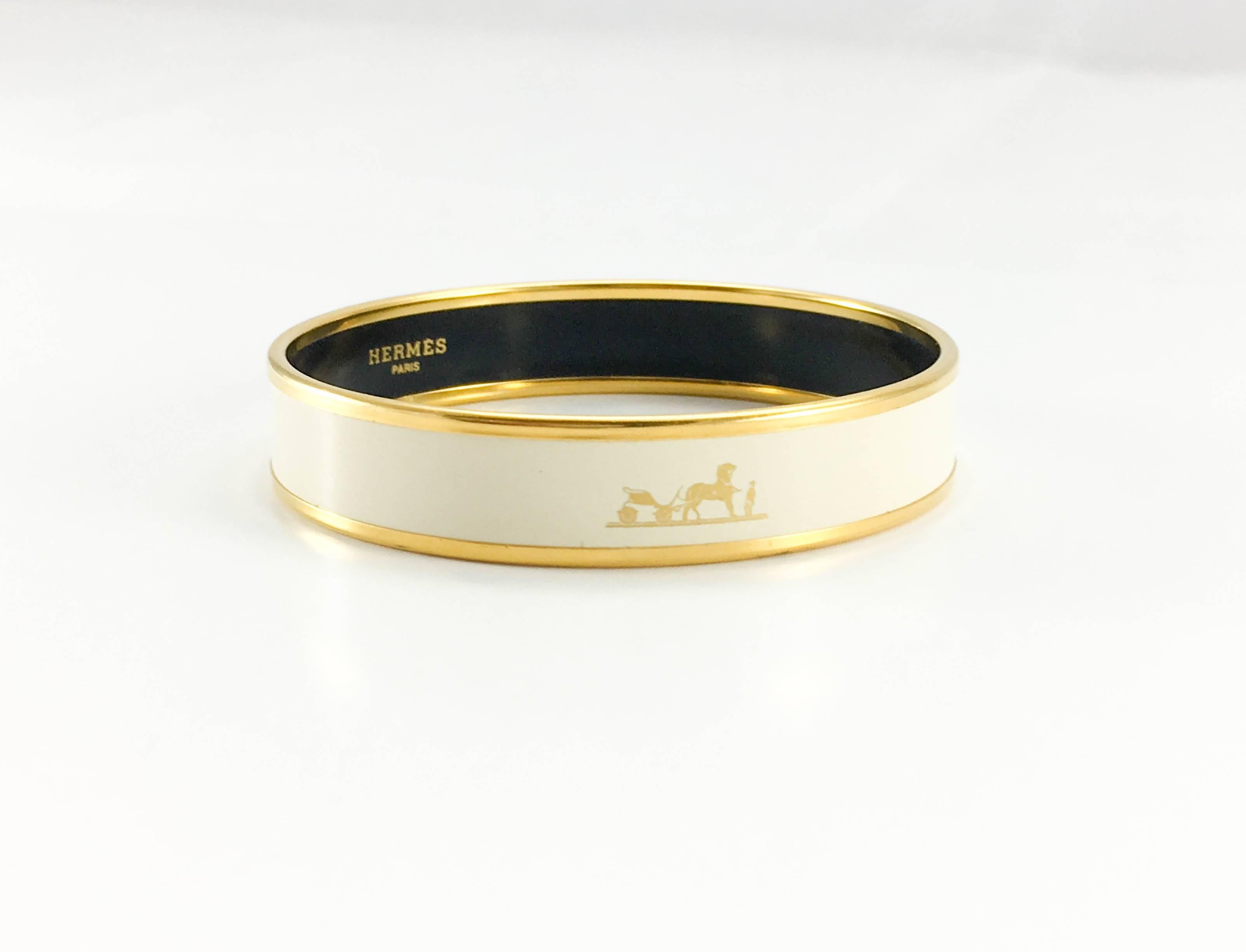 Hermes White Kelly Caleche Gold Enamel Bangle. This beautiful bangle by Hermes is made in white and gold enamel. It features 3 images of the iconic Hermes horse and carriage design, making this now discontinued design by Hermes very sought after. A