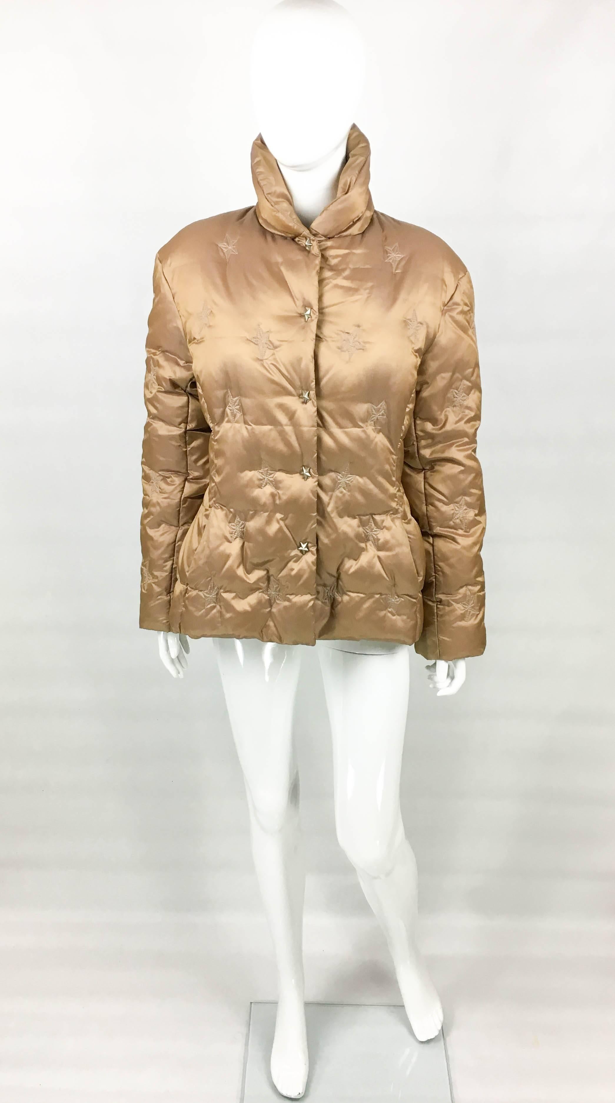 Vintage Mugler Bronze Puffer Jacket. This fabulous piece by Thierry Mugler dates back from the 1990’s. Made in nylon, the jacket is filled with duck feathers. In a beautiful shade of bronze, it features embroidered stars throughout. There are 5