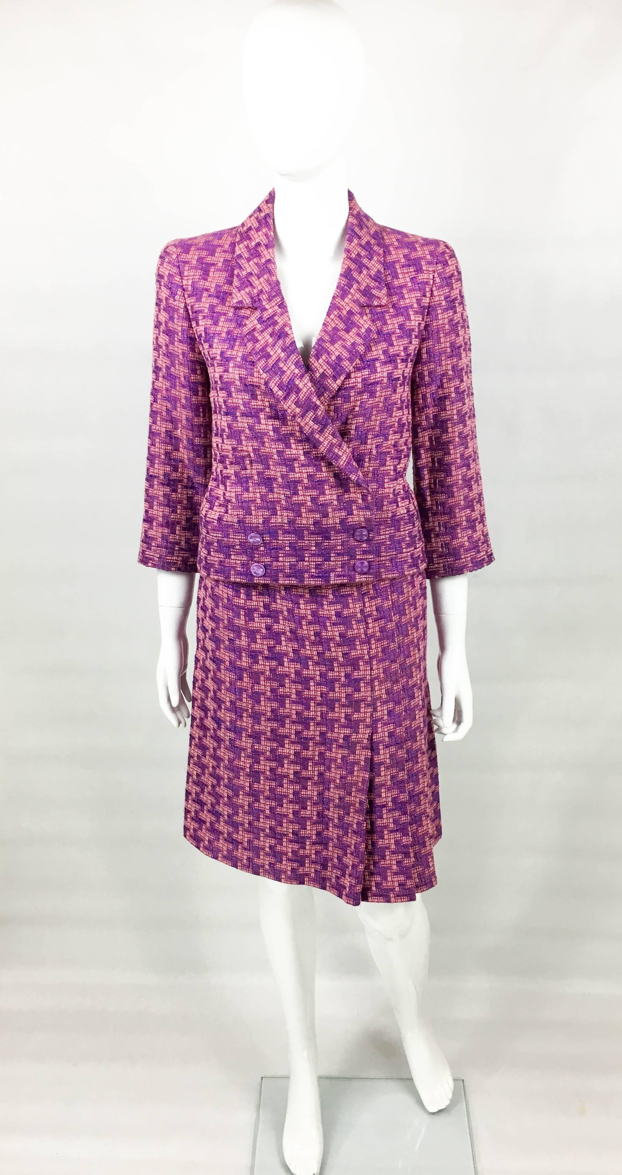 Vintage Chanel Bouclé Skirt Suit. This beautiful suit by Chanel was made for the 2001 Spring / Summer Collection. Made in a purple and pink b	ouclé, it is lined in silk. The double-breasted jacket has 4 purple logo buttons on the front. The