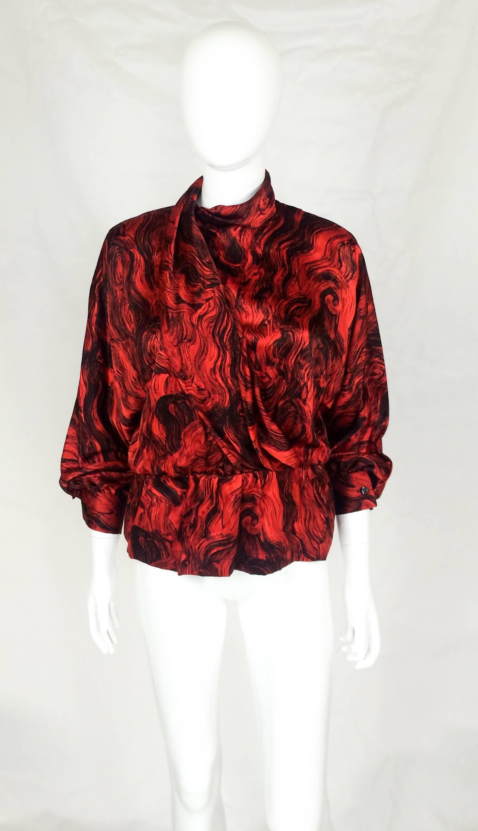 Vintage Pierre Cardin Silk Blouse. This beautiful blouse features a bold red and black abstract print, cowl collar and soft draping on the front. The waist is elasticated forming a peplum. This is an elegant and striking blouse by one of France’s