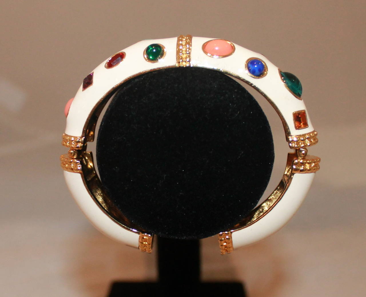 Kenneth Jay Lane White Enamel & Multi Stone Bangle. This piece is in excellent condition with no stones missing. The stones are blues, pinks, reds, and greens. 

Width- 0.65