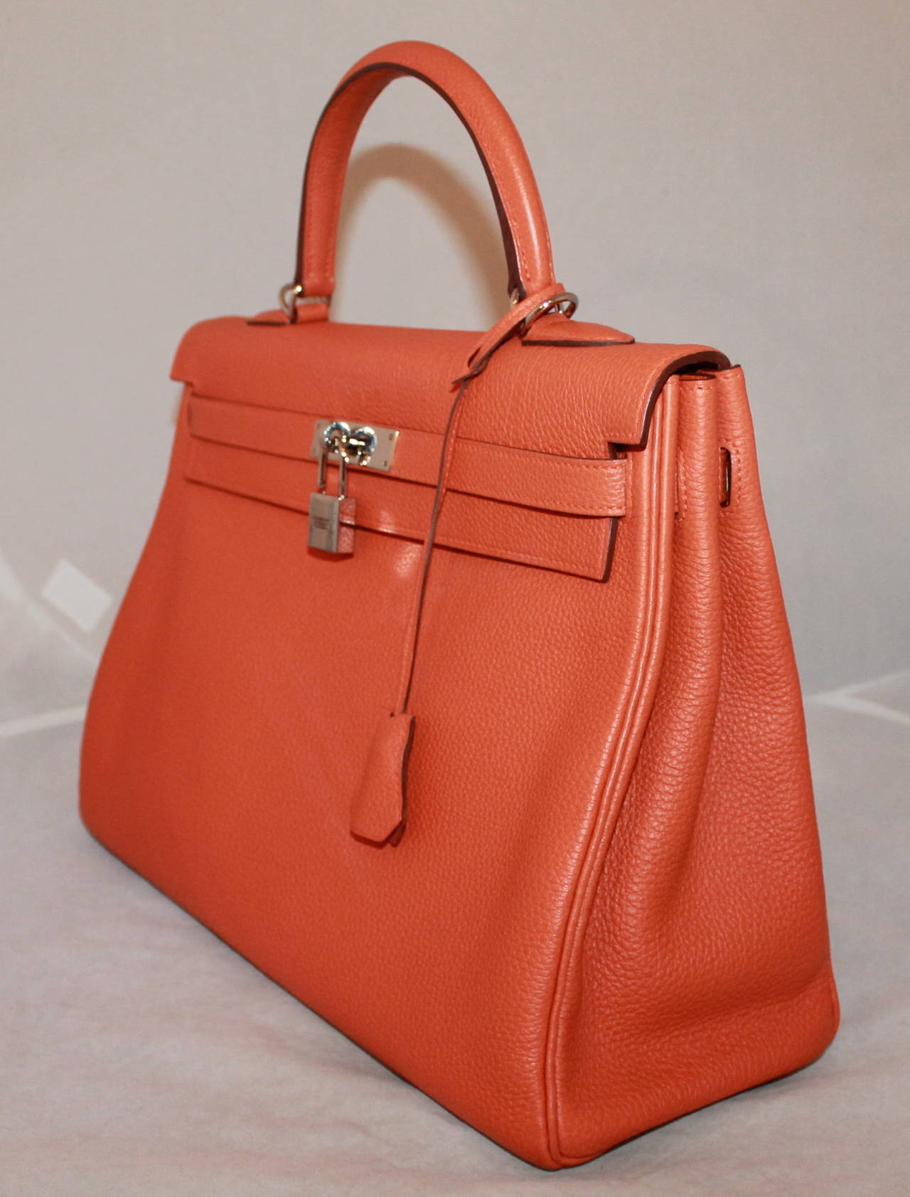 Hermes Orange Leather Kelly Handbag SHW - circa 2012. This handbag is in good condition with one minor stain on the backside of the handbag. The hardware is in good condition, however the lock shows signs of use.

Measurements:
Length-