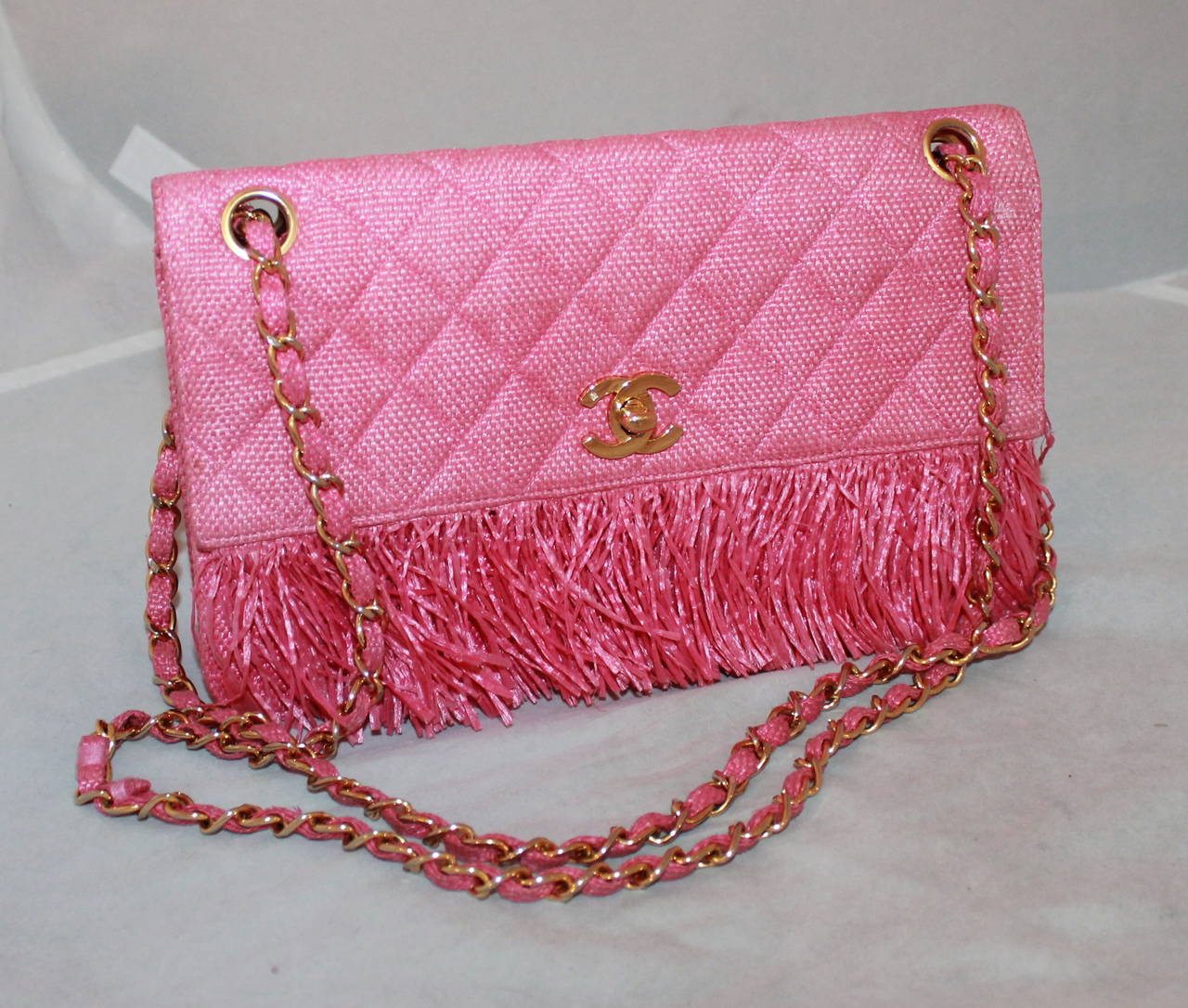 Chanel Vintage Pink Raffia & Fringe Single Flap Handbag - circa 1992. This bag is in very good condition with the exception of one area on the backside of the bag near the bottom. That area has dirt stains which appear in image #4.