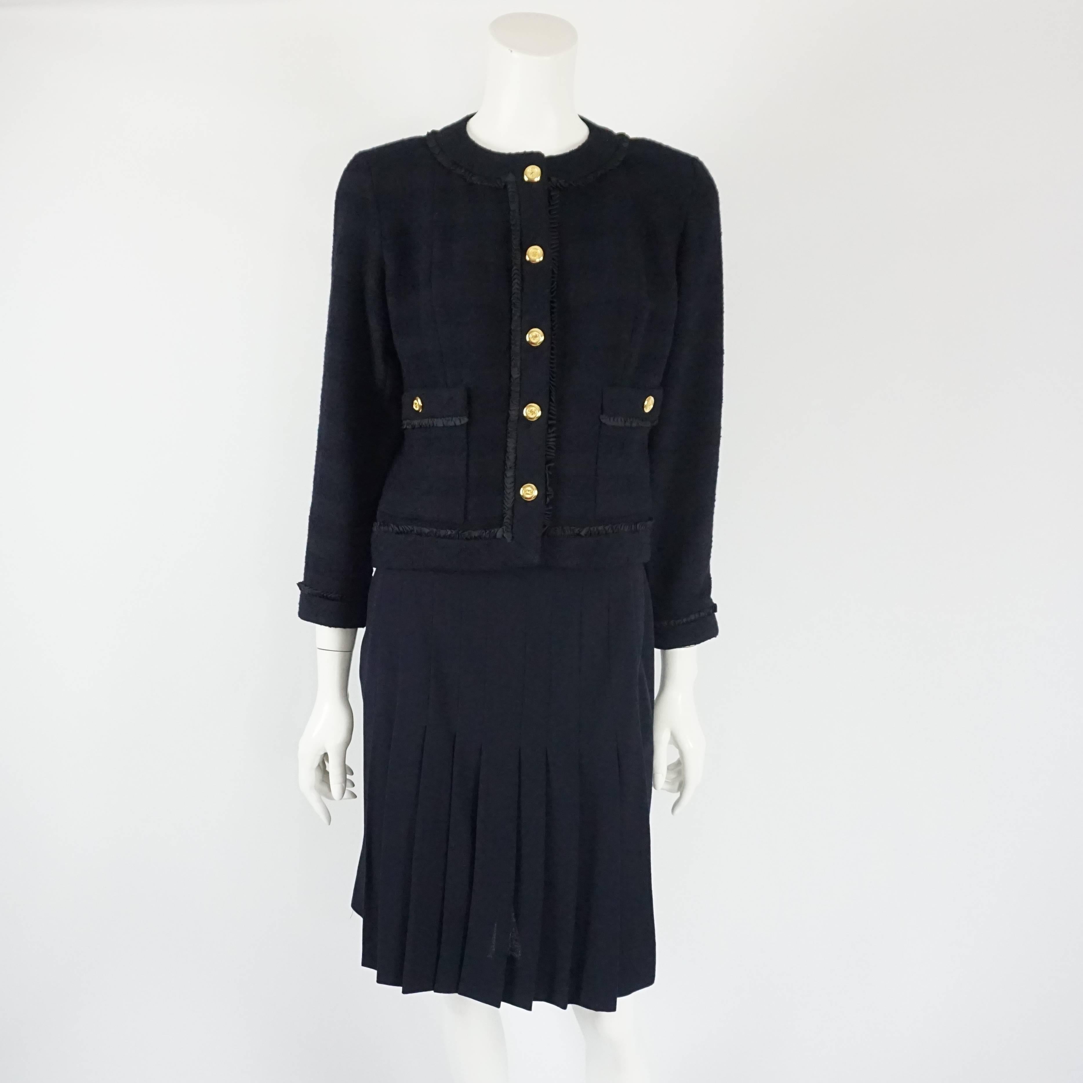 This Chanel navy skirt suit is a classic, timeless piece. It features a textured single breasted jacket with small silk ribbon detail individually attached making an illusion of a ruffle trimmed along the entire jacket, 5 front gold buttons, 2 patch