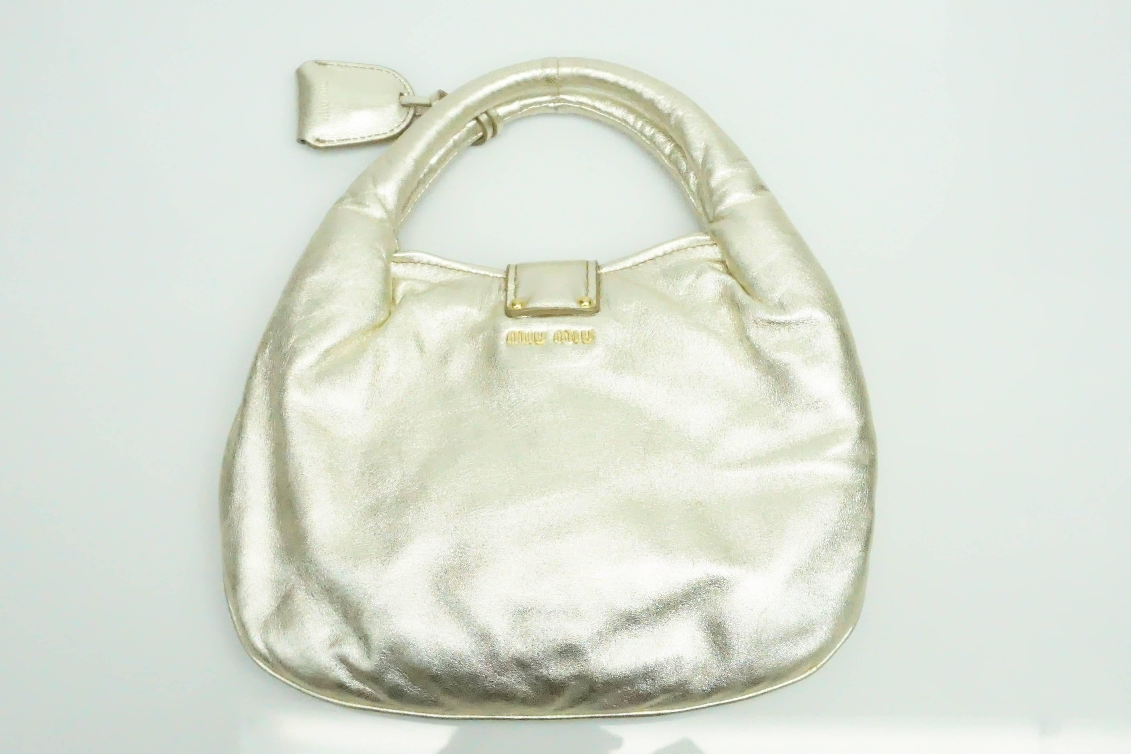 Miu Miu Gold Puffy Soft Leather Handbag  This unique gold metallic soft leather with gold hardware is in excellent condition. The handbag has a strap that goes across the opening that can be locked. There is a small pouch attached to the straps that
