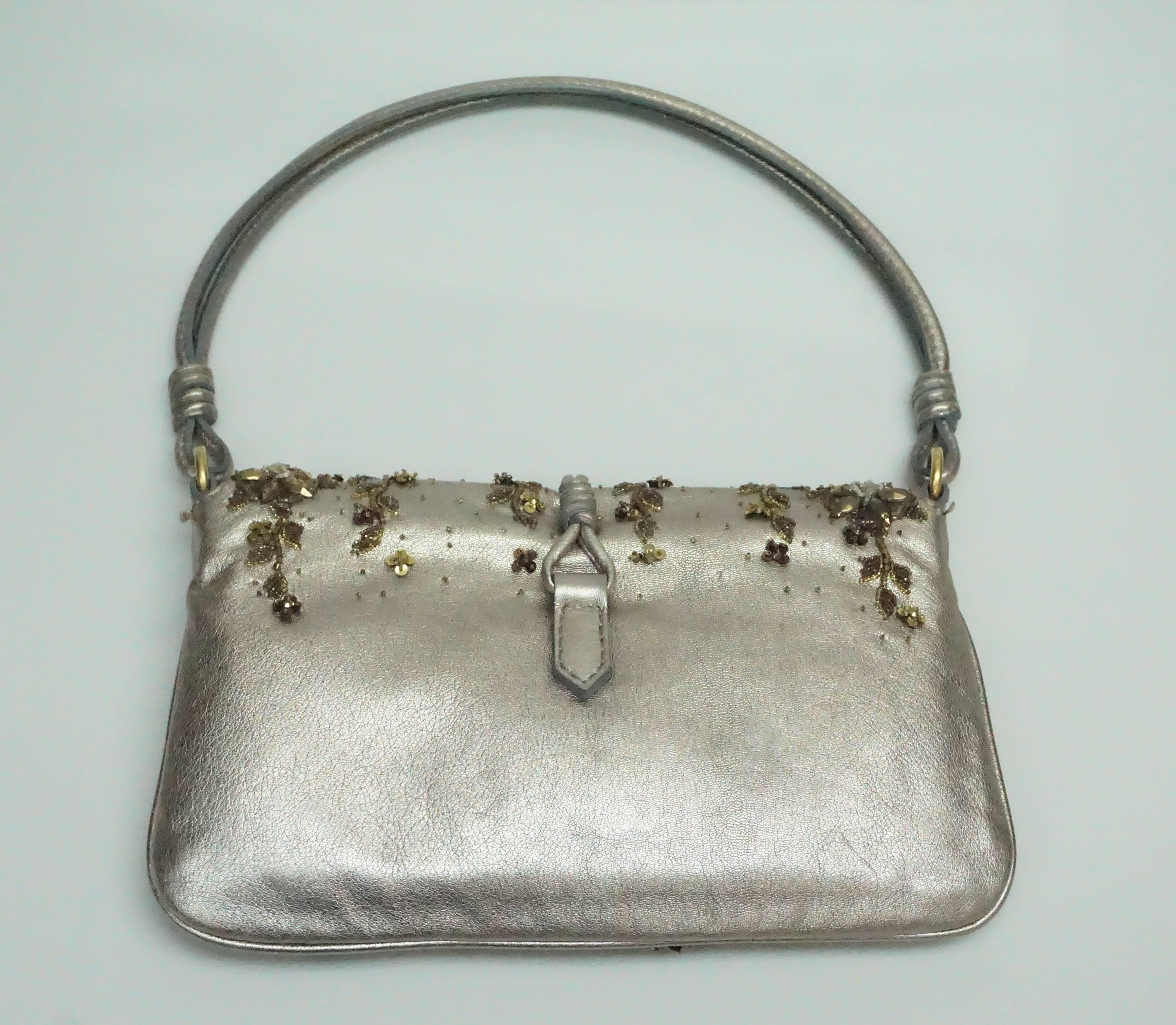 Valentino Beaded Gold and Bronze w/ Floral Embellishments  This gorgeous Valentino evening bag is in excellent condition. The bag has a slight flap with a heavy gold medallion of the Valentino logo attached to a string.  The front of the bag has
