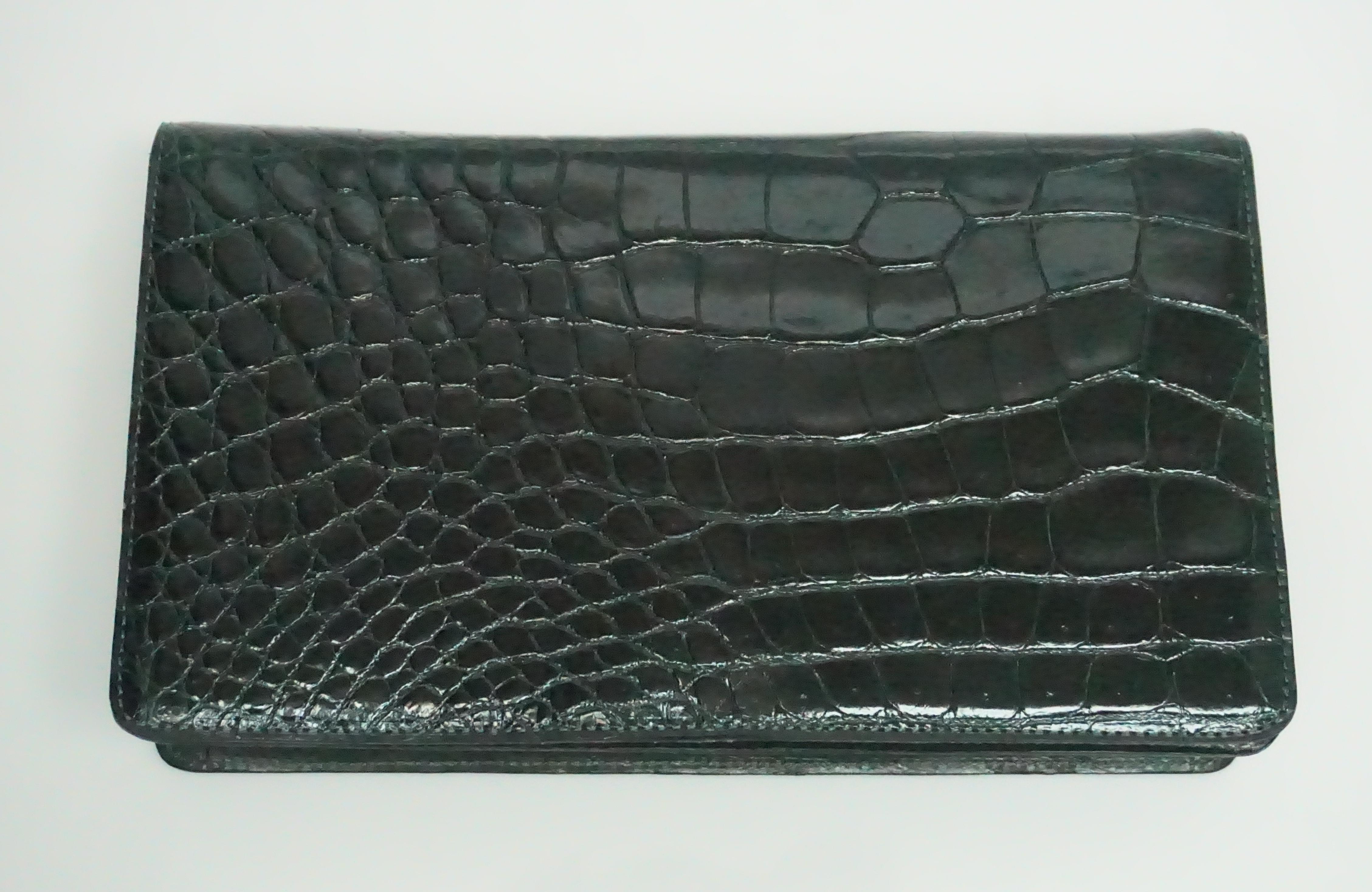 Saks Fifth Avenue Dark Green Alligator Clutch  This beautiful alligator clutch is in excellent condition. The flap that opens and closes the clutch is detailed with a magnetic button. The inside of the clutch has one side pocket that closes with a