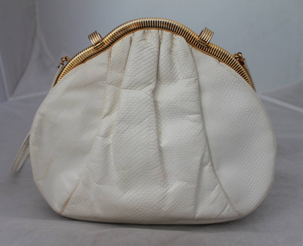 Judith Leiber 1980's White Lizard Evening Bag with Pink Stones. This bag is in good vintage condition with a couple smudges near one clasp and on the back right. It has a longer strap or can be used as a clutch.

Measurements:
Length-