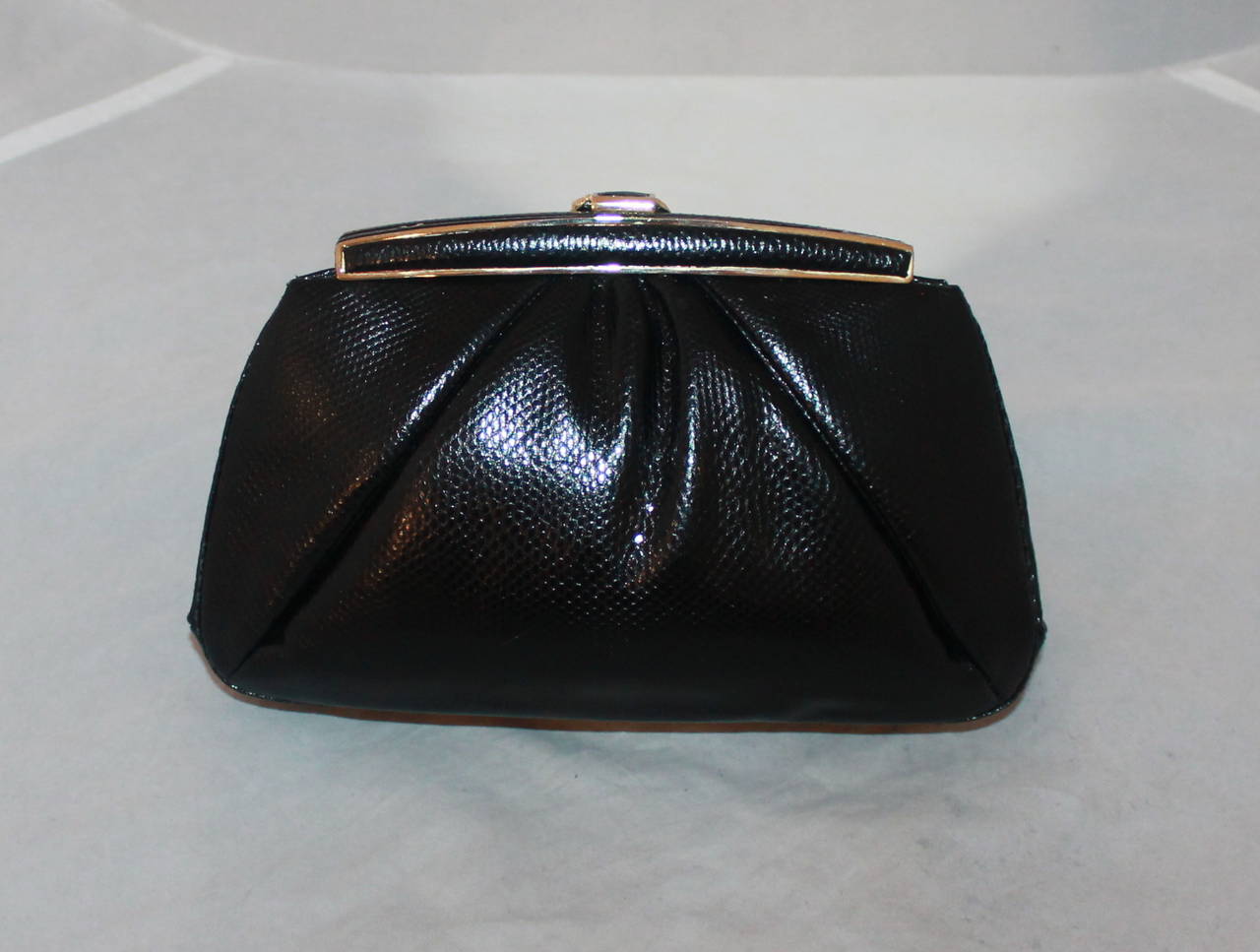 Judith Leiber 1980's Vintage Black Lizard Evening Bag with Gold Knot Clasp. This bag is in excellent condition and comes with a coin purse, compact, comb, compact case, and duster. 

Measurements:
Length- 5.5