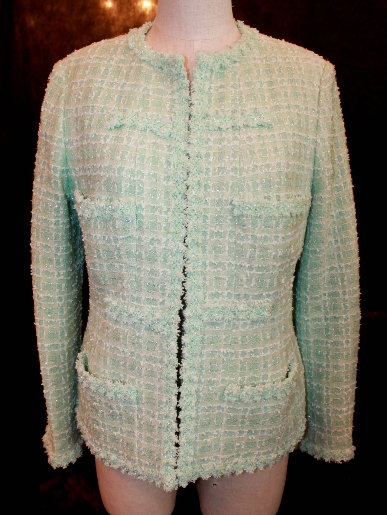 Chanel 1995 Vintage Mint Tweed Jacket with 4 Pockets - 42. This jacket is in excellent condition. The tweed trimming has a clear tinsel-like material woven into it. It does not have buttons to close the jacket.

Measurements:
Bust- 37