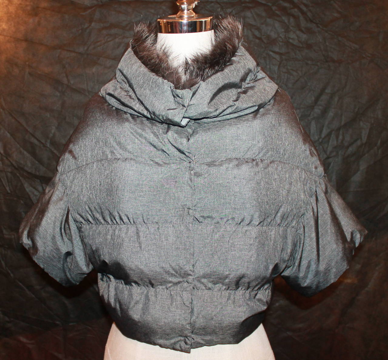 Brunello Cucinelli Charcoal Cropped Short Sleeve Puffer Jacket with Fur - S. This jacket is in excellent condition with little wear. The seam of the shoulder runs very long in accordance with the jacket's style. 

Measurements:
Bust- 34