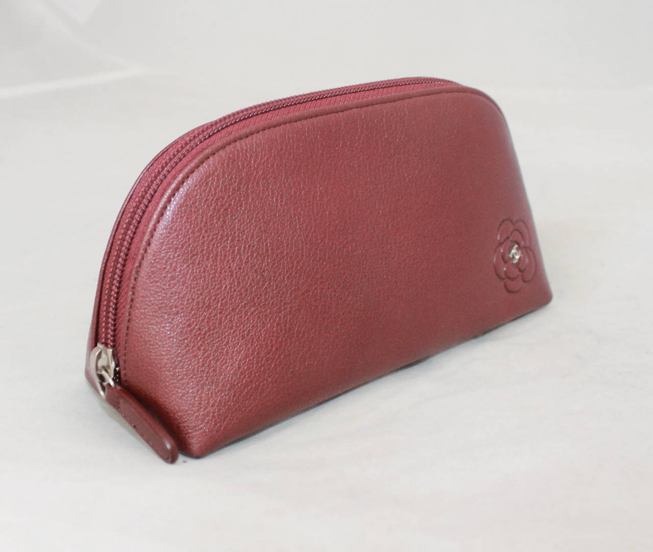 Chanel 2010 Burgundy Leather Make-Up Case with Camelia Motif. This makeup case is in excellent condition with nearly no signs of use.

Measurements:
Length- 4