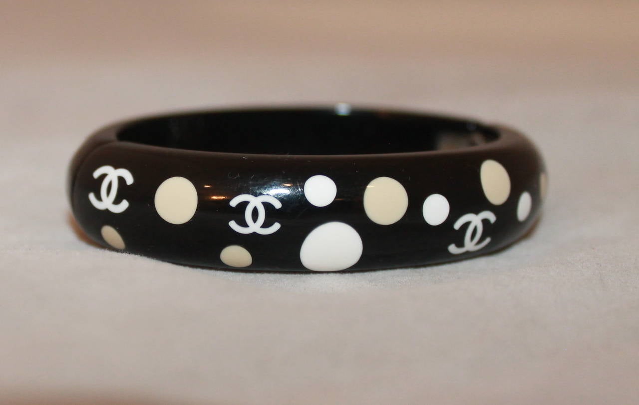 Chanel 2005 Black, White & Beige Polka-Dot Enamel Bangle. This bangle is in excellent condition and magnetically closes. 

Width- 0.65