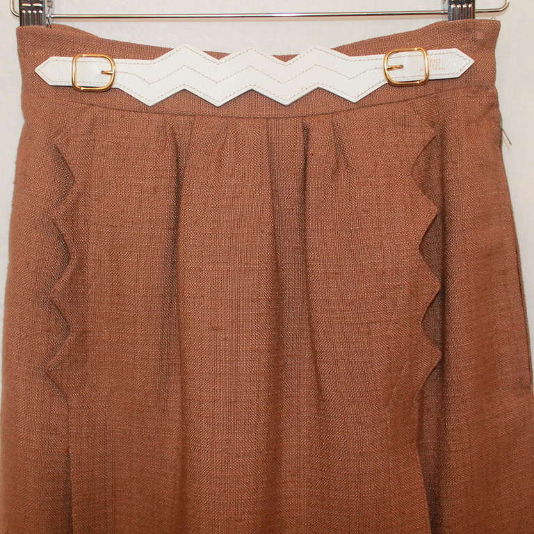 Hermes Tan Skirt with white leather belt & gold buckle on waist. Flap on the front has an edge detail and skirt is in excellent condition. Size 36.
Measurements:
Waist- 24"
Hips- 34"
Length- 22.5"