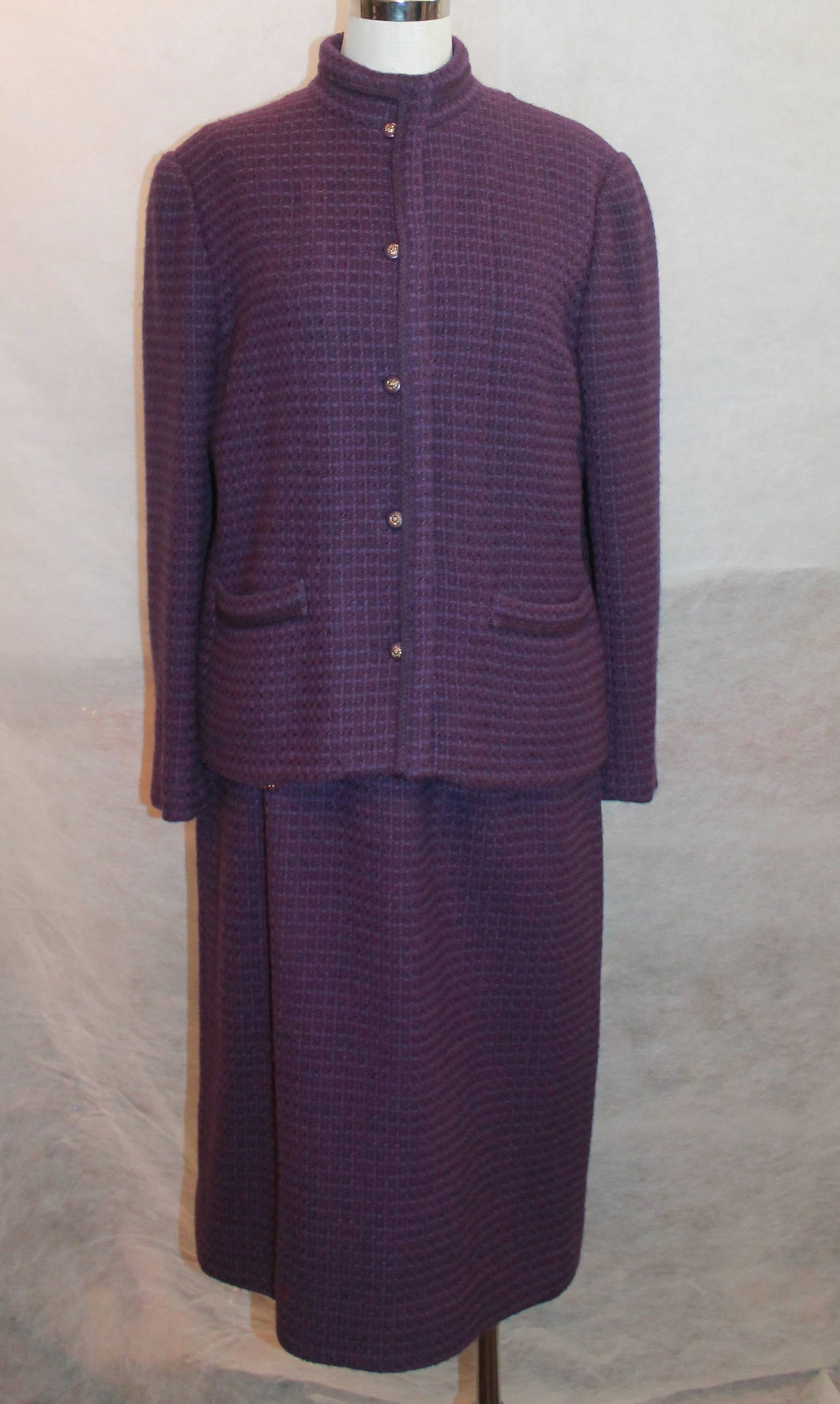 Chanel 1970's Vintage Purple Tweed Wool Skirt Suit - 44. This suit is in very good vintage condition with very minor wear. It has 2 front pockets and has an elevated purple trimming. The buttons have the lion emblem on them as well.