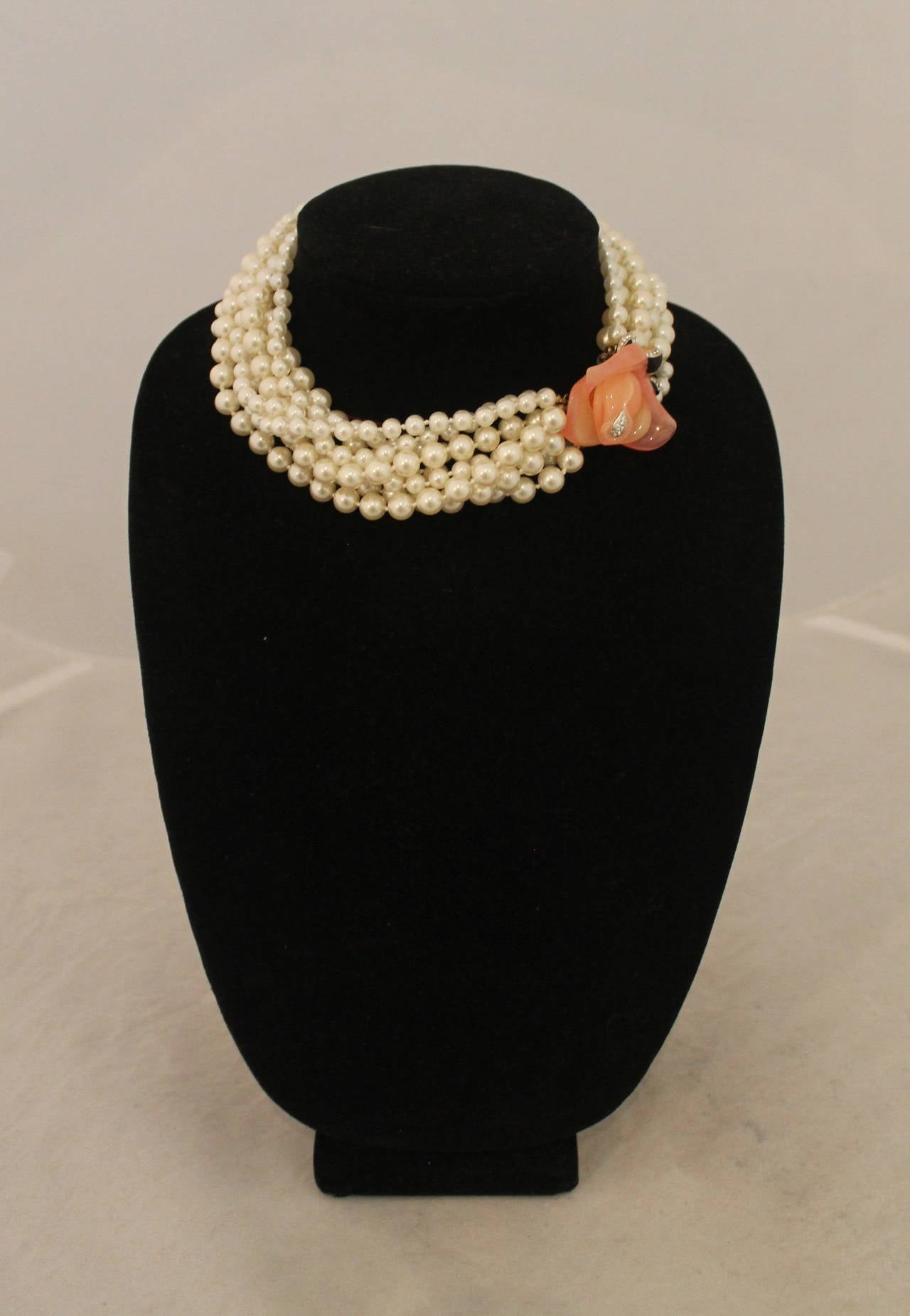 Kenneth Jay Lane 1990's 8-Strand Pearl & Rose Motif Necklace. This necklace is in excellent vintage condition with very minor wear. The strands of pearls are differing sizes and hook together by a peach colored rose clasp. It has a Lucite look and