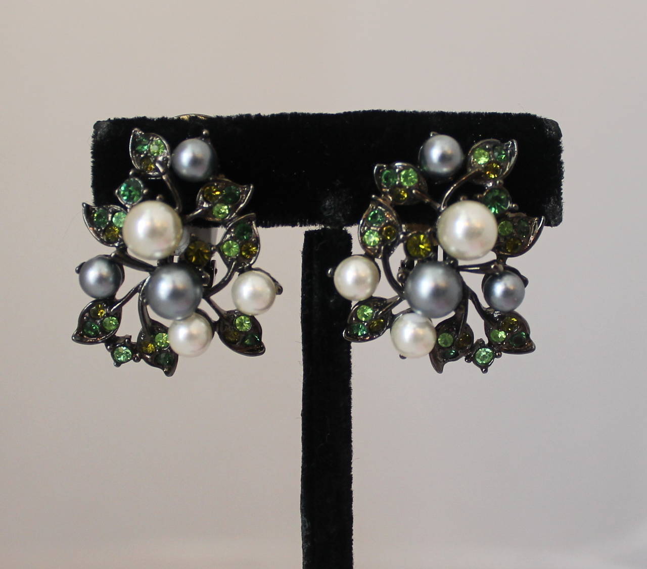 Orecchini a clip con perle e strass verdi di Kenneth Jay Lane del 1990. Questi orecchini sono in ottime condizioni vintage e sono in tonalità palladio. Le perle sono di colore avorio e grigio, mentre gli strass sono di colore verde più chiaro e più
