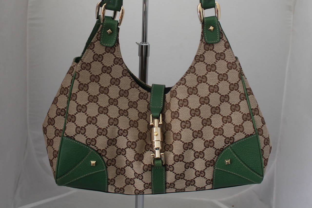 Gucci Brown Fabric and Deep Green Leather Trim Printed Monogram "GG" Shoudler Bag with Gold Hardware and Closure. This bag is in fair condition with some general wear on the fabric, corners, bottom and some leather wear.