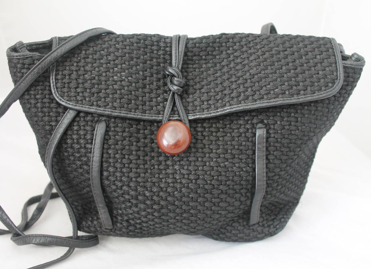 Bolso crossbody vintage de rafia negra tejida de los años 80 que se puede llevar como mochila. El bolso tiene solapa con botón de madera para el cierre, tiras finas de cuero y ribetes.

Medidas:
Altura: 9 