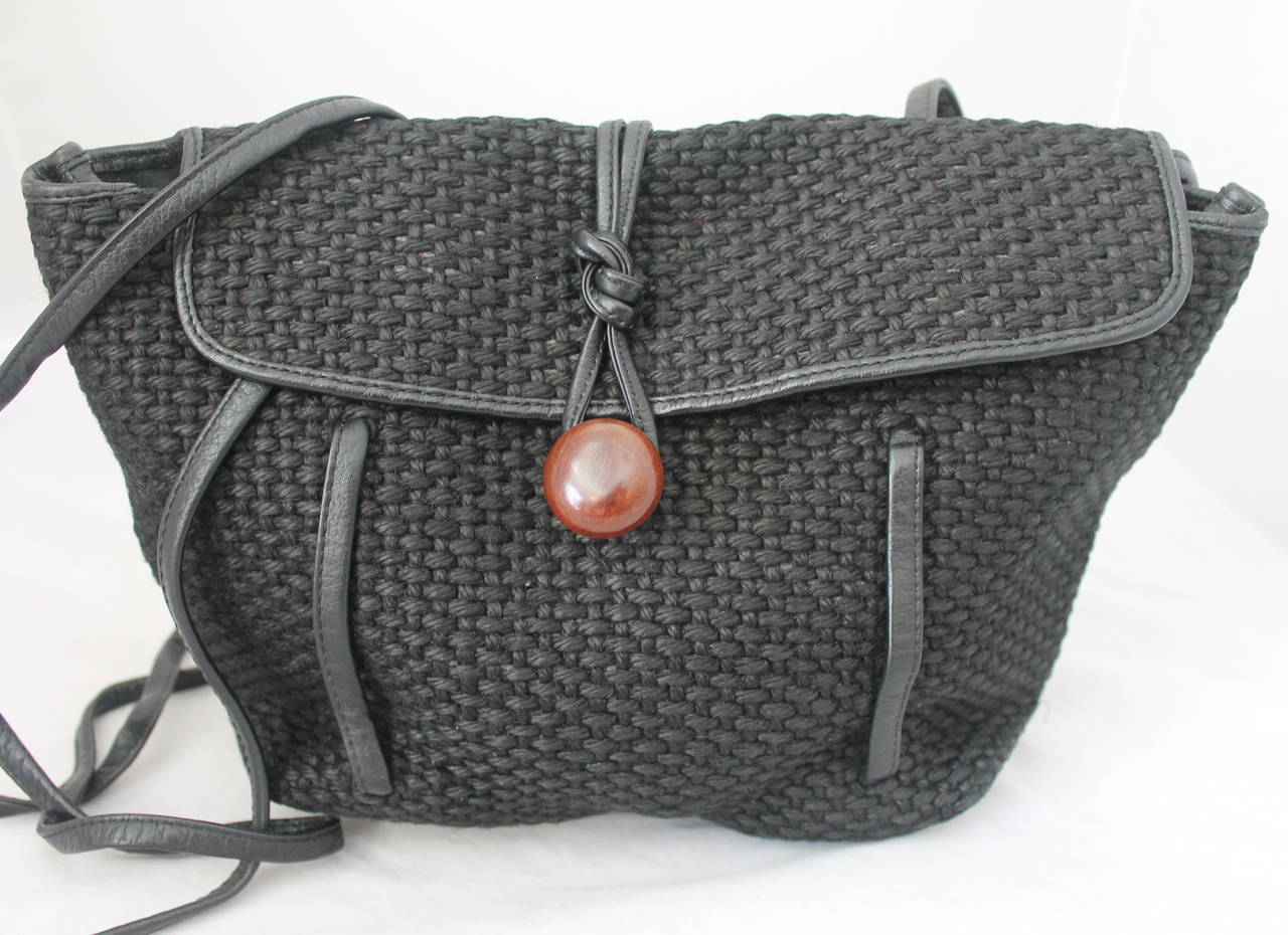 1980s Vintage Black Woven Raffia Crossbody Bag that can be Worn as a Backpack. Bag has Flap with Wood Button for Closure, Thin Leather Straps and Trim.

Measurements:
Height: 9 