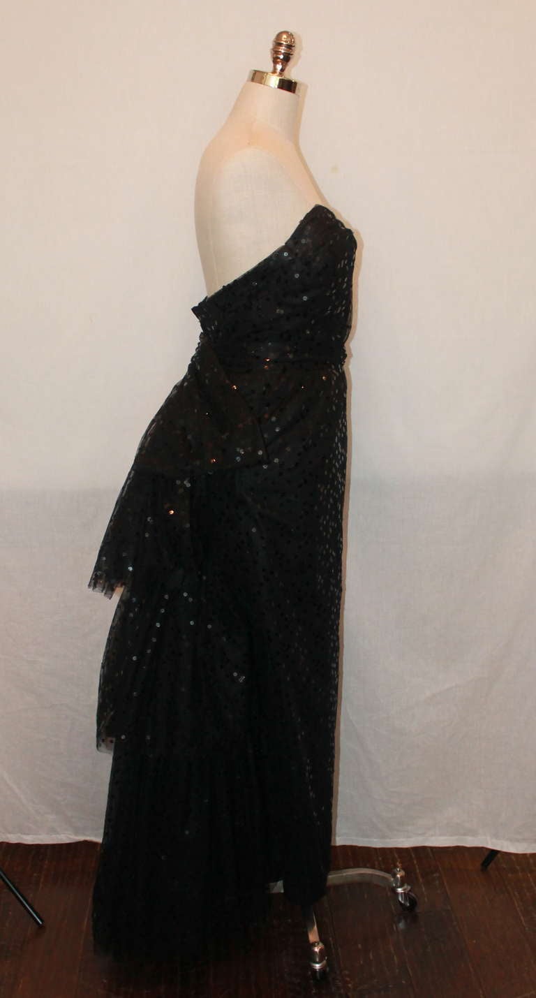 John Anthony black silk netting strapless gown. It has a sweetheart neckline with sequined netting and 3 tiered ruffles on the backside. The gown also has a sash with a bow on the back. It is in excellent condition and a size