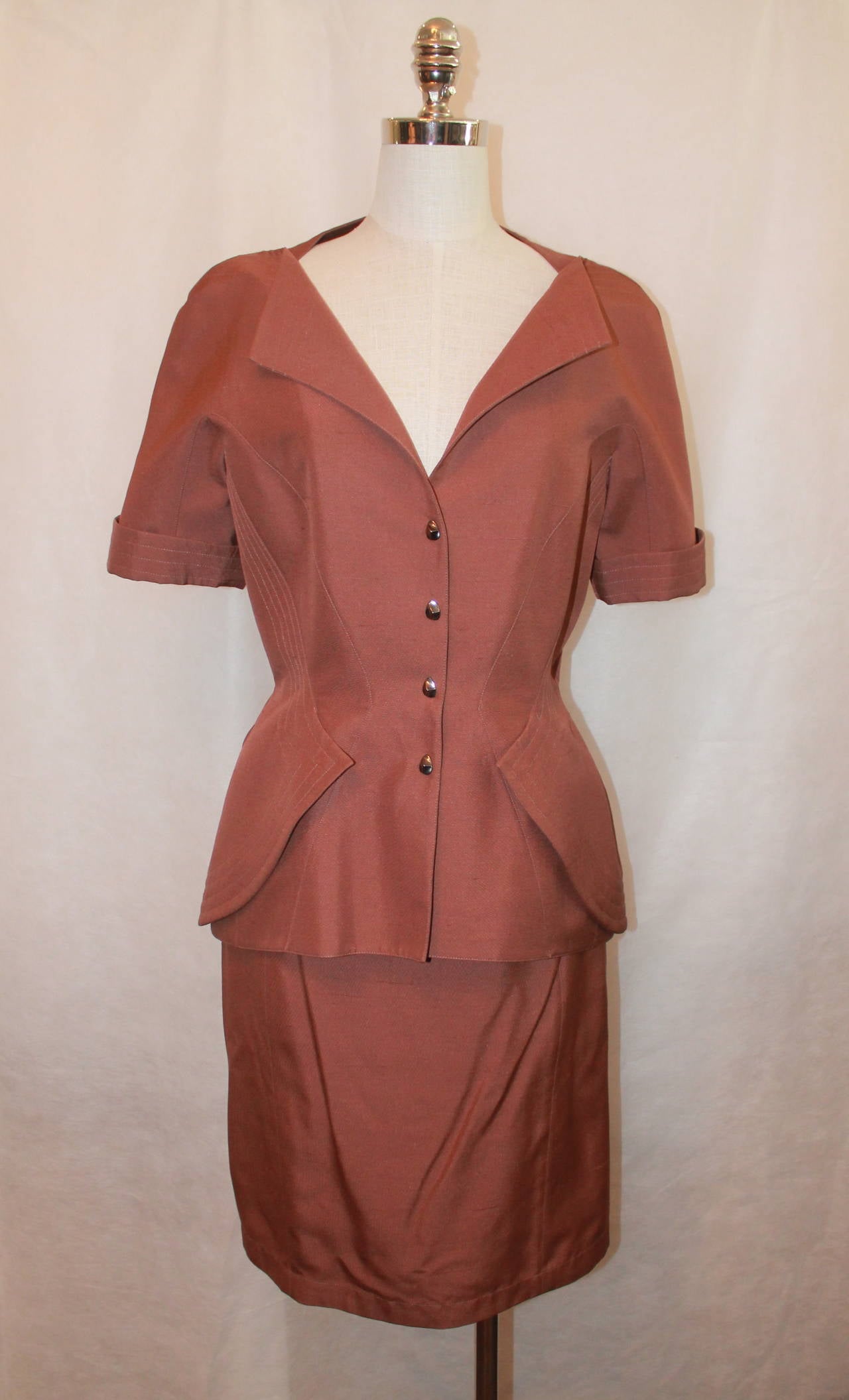 Thierry Mugler 1980's Brown Short Sleeve Skirt Suit - 44. This piece is in excellent vintage condition with light wear. It is 100% acetate with a silk lining. The front of the jacket also has 2 accent flaps. 

Measurements:

Jacket
Bust- up to