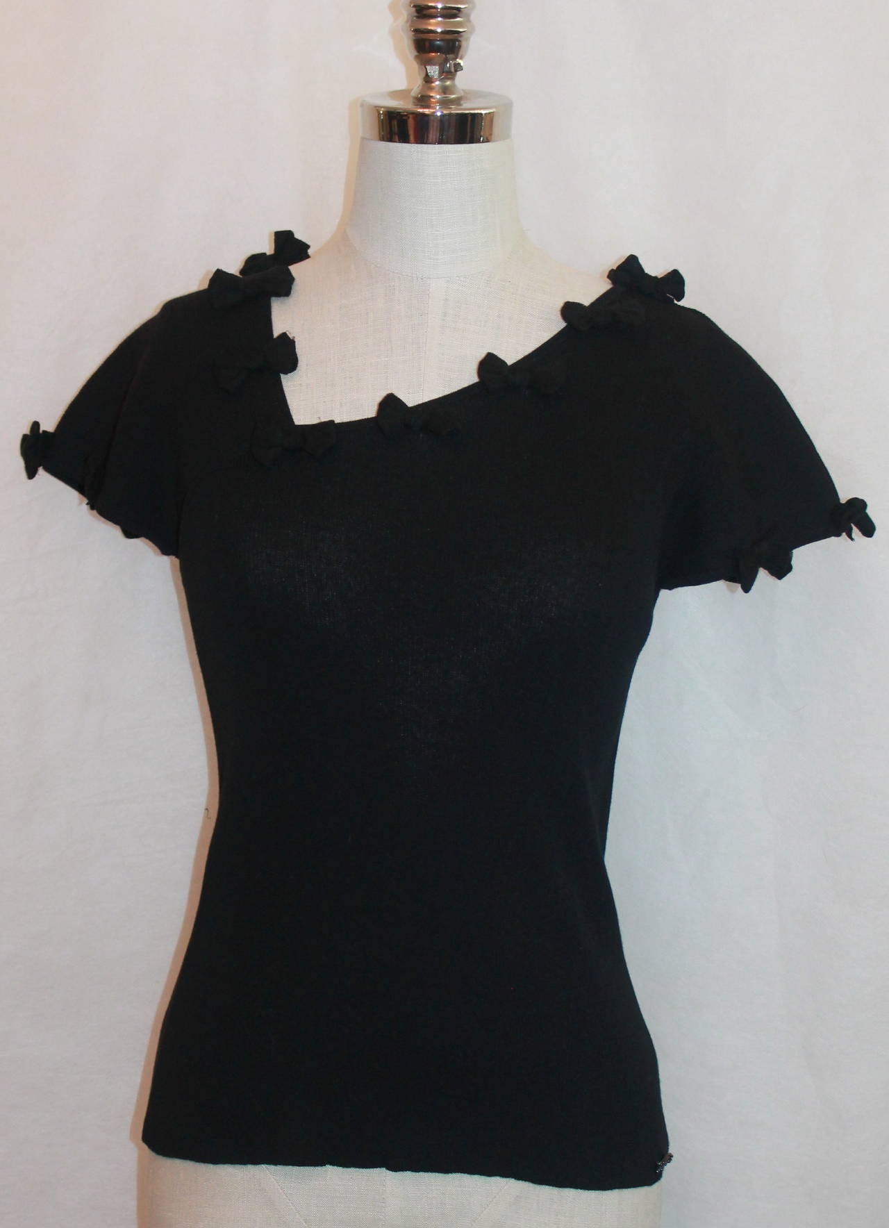 Chanel 1999 Vintage Black Shirt with Small Bow Details - 40. This shirt is in very good condition and is a knitted cotton blend. The bows are on the neckline and sleeves. 

Measurements:
Bust- 29