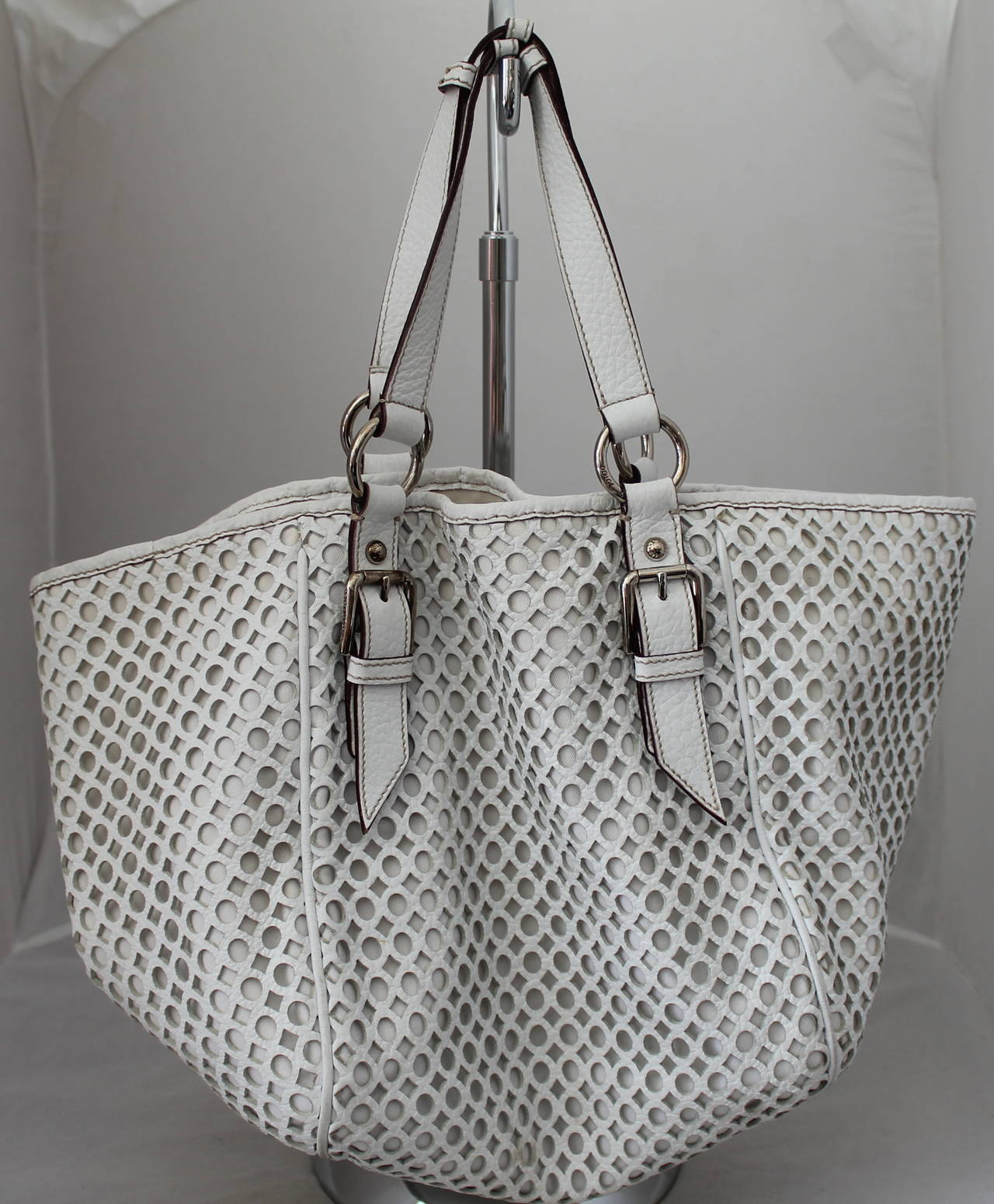 Dolce & Gabbana White Perforated Leather Shoulder Bag. This bag is in very good condition with the only visible wear being on the inside lining. There are some discolorations and stains, but the outside is in excellent shape. The bag has silver