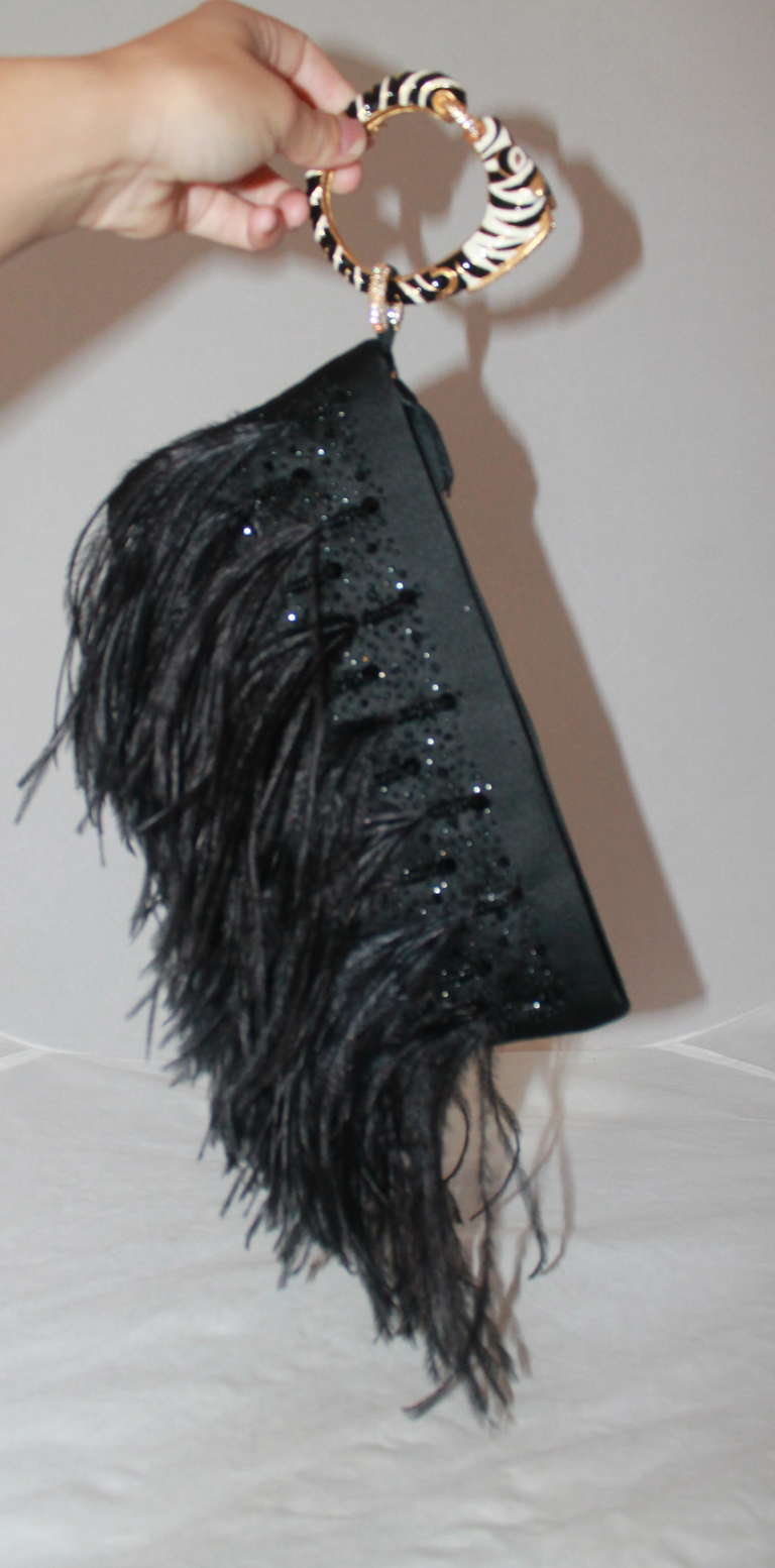 Valentino Black Ostrich Feather Clutch with Black Rhinestone Detail. This clutch is in impeccable condition with a detachable zebra & rhinestone bracelet.
Measurements:
Height- 8