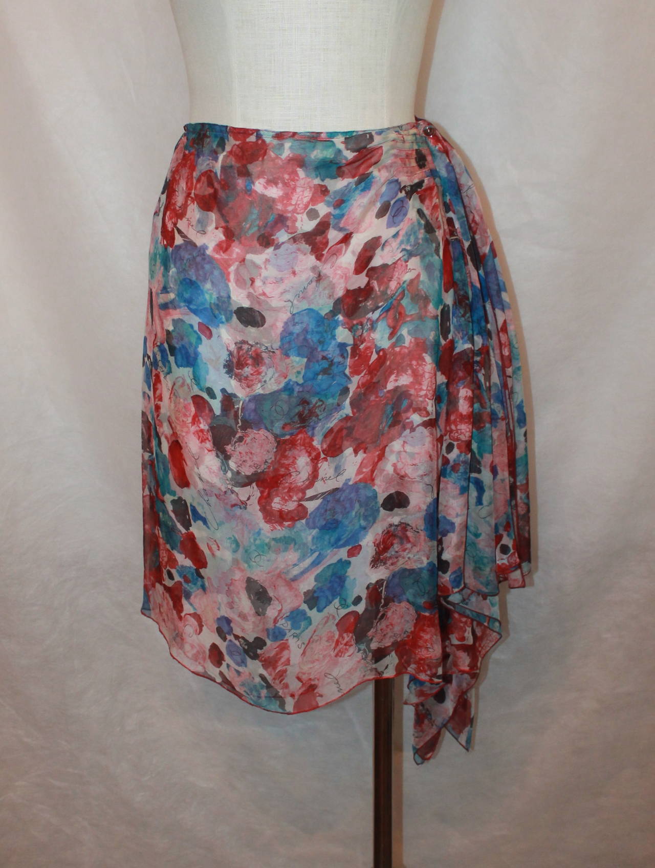 Chanel 2000's Multi-Color Floral & Chanel Printed Silk Chiffon Skirt - 38. This skirt is in excellent condition and is lined. The skirt has a gathering on the right side that hangs below the length of the skirt. 

Measurements:
Waist- 26