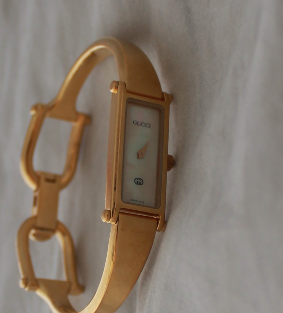 Gucci Goldtone Mother of Pearl Bracelet-Style Watch. This watch is in excellent condition and is thin. The face is mother of pearl and there are no numbers on it. It  was a Gucci buckle closure.

Circumference- 6.5