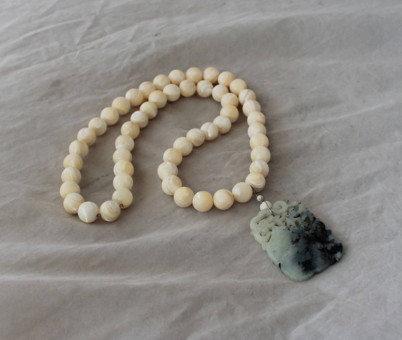 2000's Mother of Pearl Necklace with Carved White Jade Pendant. This piece is in excellent condition. The jade is carved into an Asianic design.

Necklace Bead Width- 0.5