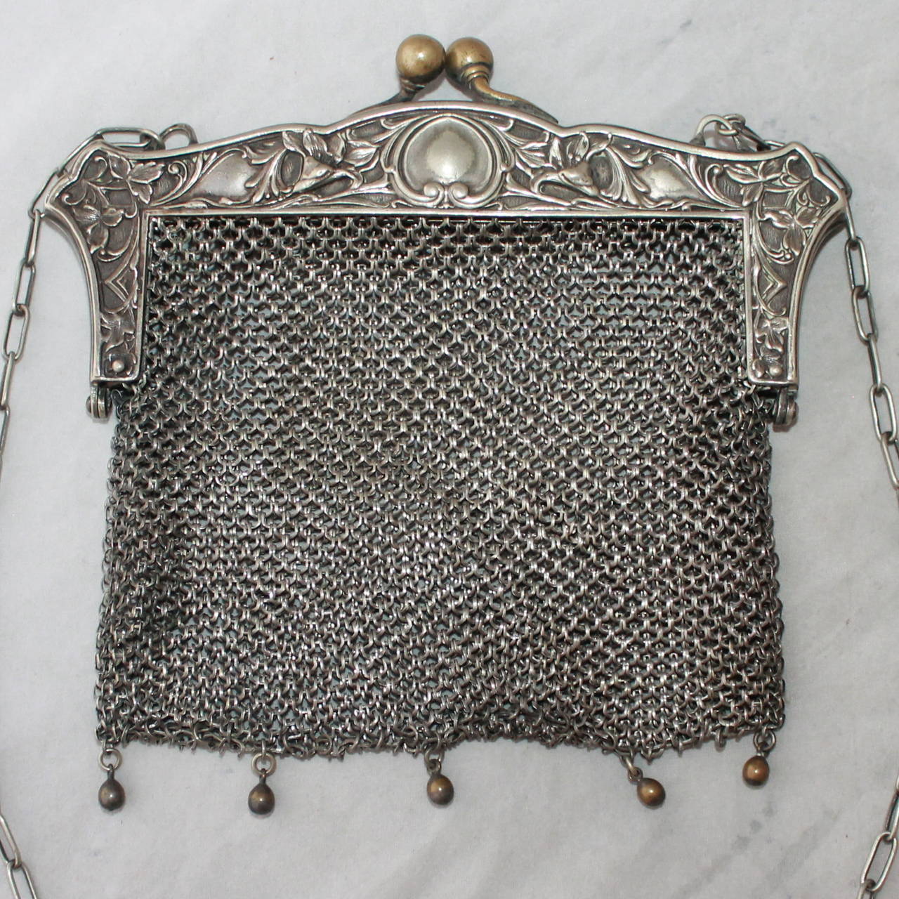 Edwardian Antique JWR Co. German Silver Chainmail Bag. This bag is in good condition for an item that is nearly 1000 years old. The design on the top shows signs of age as the silver is darkening. The clasp and beads hanging from the bottom are a