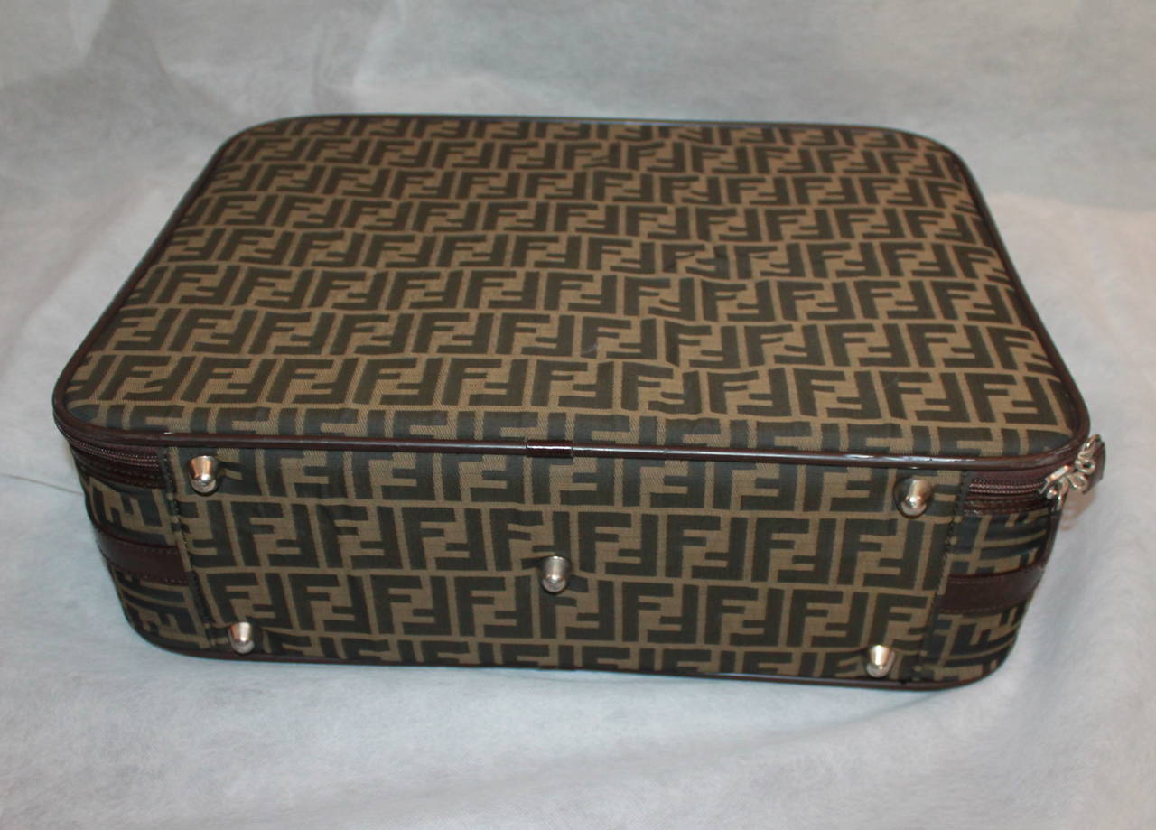 Fendi Monogram Printed Suitcase with Leather Handle & Trim. This bag is in fair condition with noticeable wear. There is scuffing on the plastic trim around the bag, markings on the top leather & handle, a slight mark on the inside, and one of the