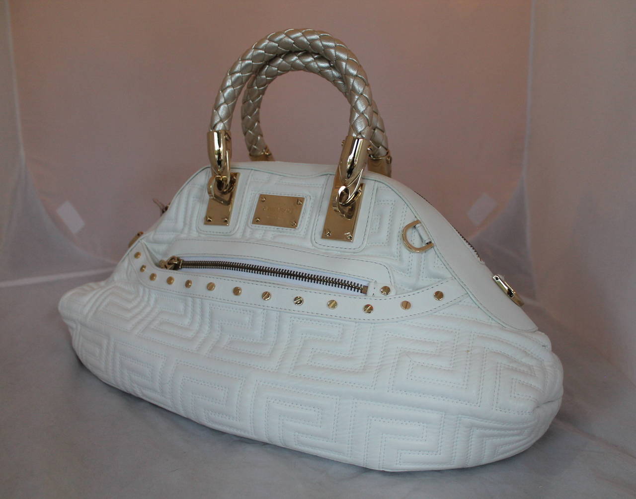 Versace Couture White Quilted Leather Handbag with Gold Braided Handle GHW. This bag is in excellent condition with only one slight spot near the zipper shown in image 5. It does not come with the longer strap.

Measurements:
Height- 8