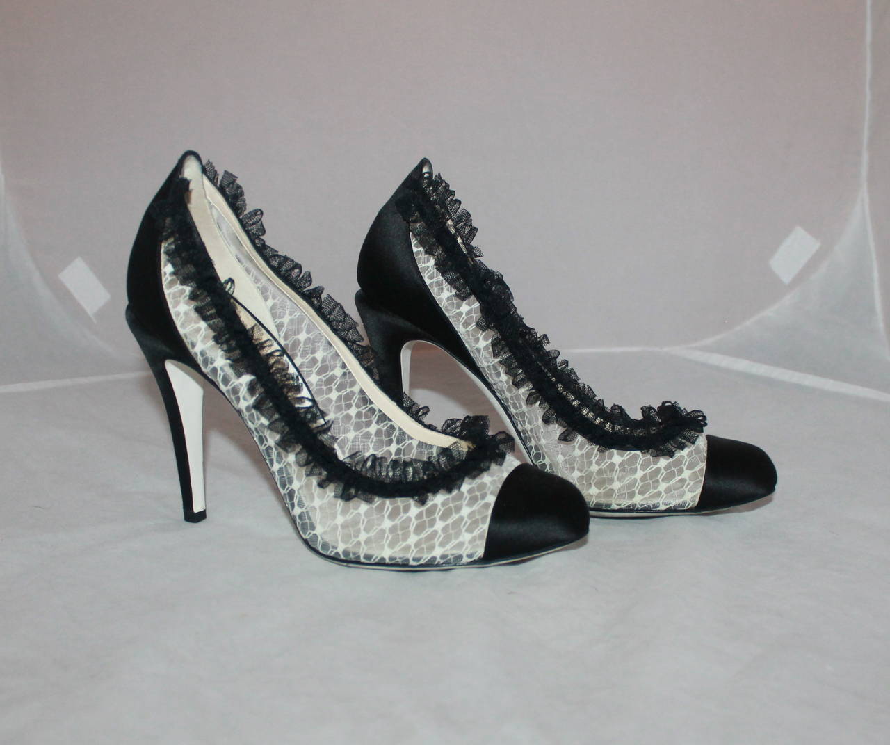Chanel Ivory & Black Lace Pumps with Ruffle Trim - 40. These pumps are in excellent condition and have moderate wear on the bottom shown in image 5. The peep-toe and the back heel are satin and have a studded 