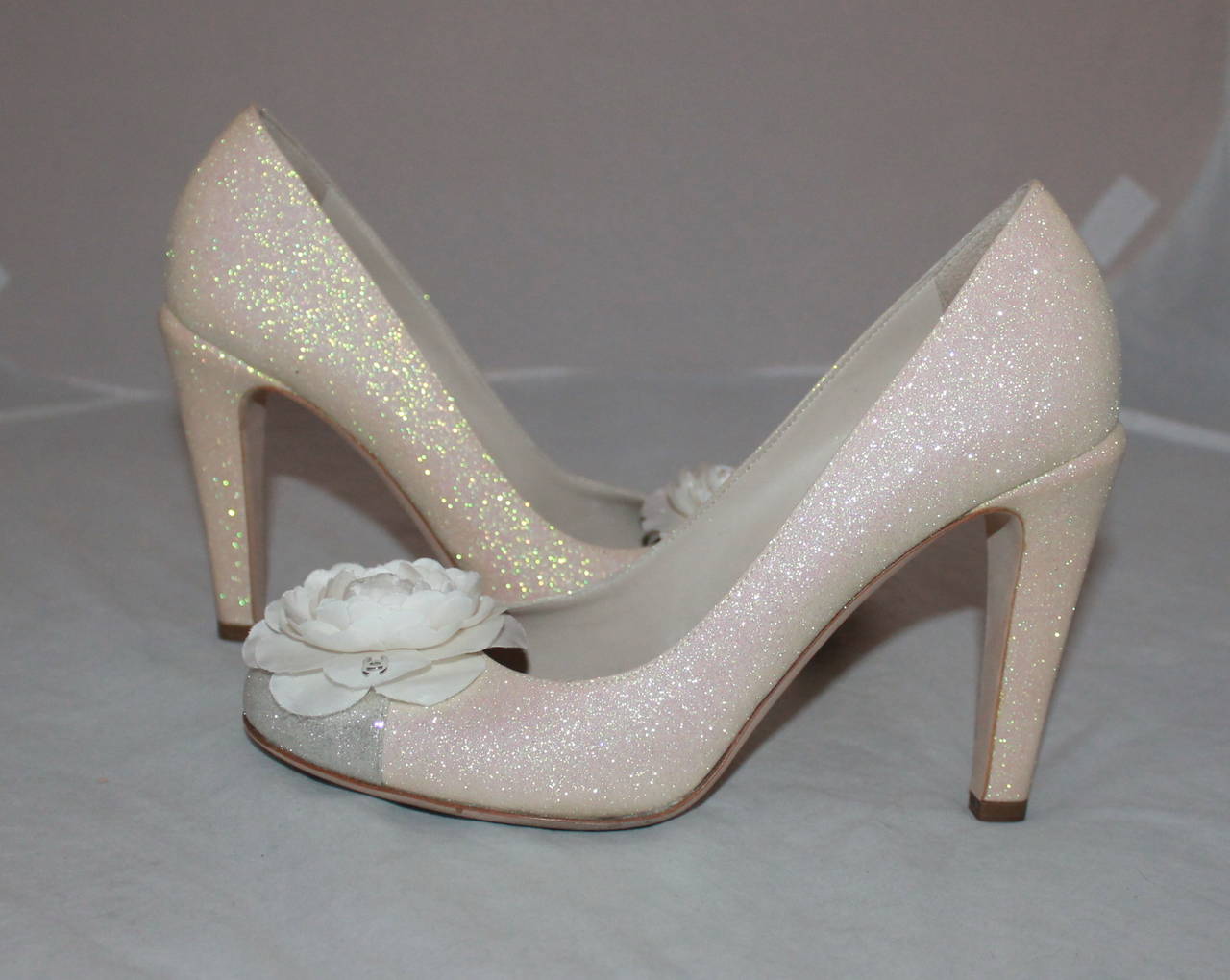 Chanel Ivory & Silver Glitter Pumps with Front Camellia - 40. These shoes are in excellent condition and have a silver toe with an ivory body. The camellia has a silver 