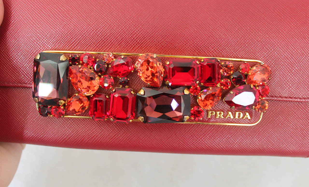 Prada Red Saffiano Leather Jewelled Wallet Clutch - rt $1,450. This bag is in excellent condition and has multi-tone red rhinestones on the clasp. It also has gold hardware. 

Height- 3.65
