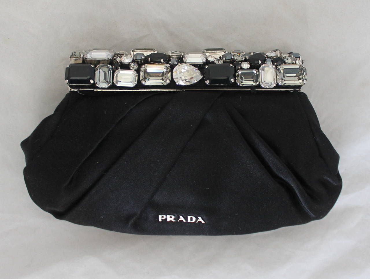 Prada Black Satin Clutch with Rhinestone Cluster Handle SHW rt. $1,460. This bag is in excellent condition and has a light pink lining. The rhinestones are different tones of greys, black, and clear. 

Measurements:
Height- 4