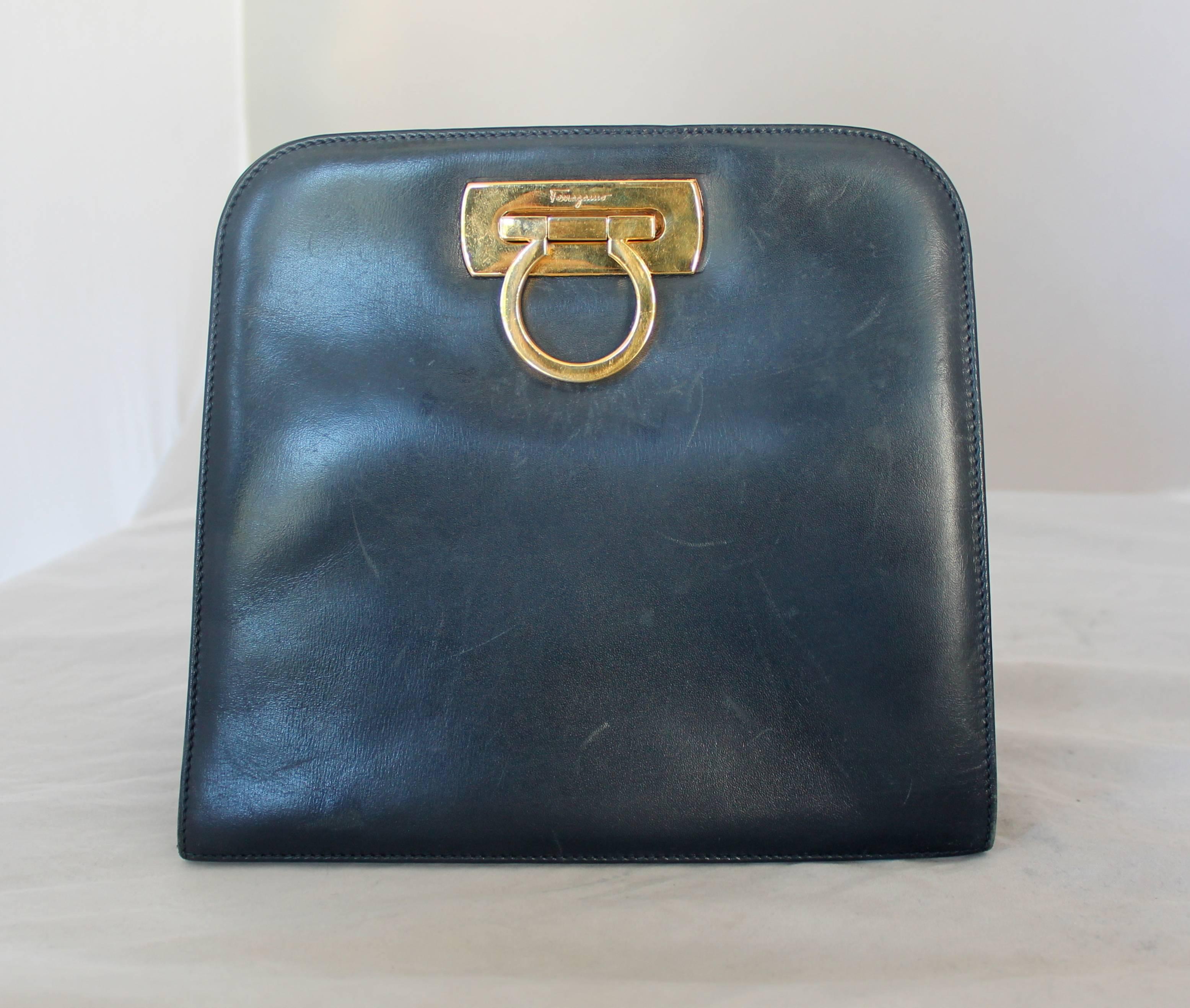 Salvatore Ferragamo Vintage Navy Leather Square Clutch/Crossbody Bag - GHW - Circa 80's

This bag is in fair condition with marks on the front, bottom, and back of bag. This bag is square shaped and has gold hardware with a gold chain. This bag