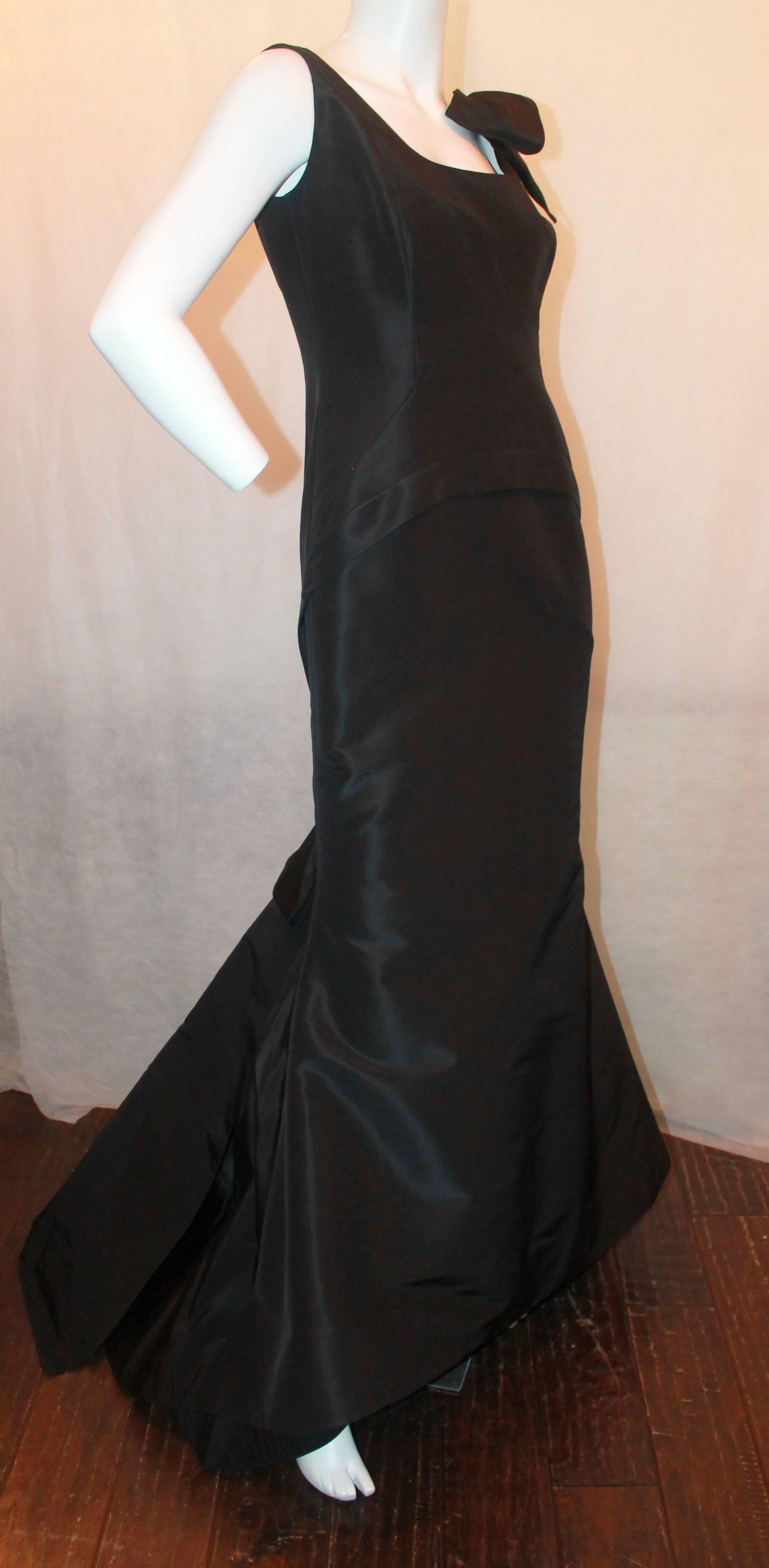 Oscar de la Renta Black Silk Taffeta Bustled Ball Gown - 8. This beautiful gown from 2012 is in excellent condition and is sleeveless with a bow on the left shoulder. It has a scoop neckline with a fitted torso and a bustled train in the back